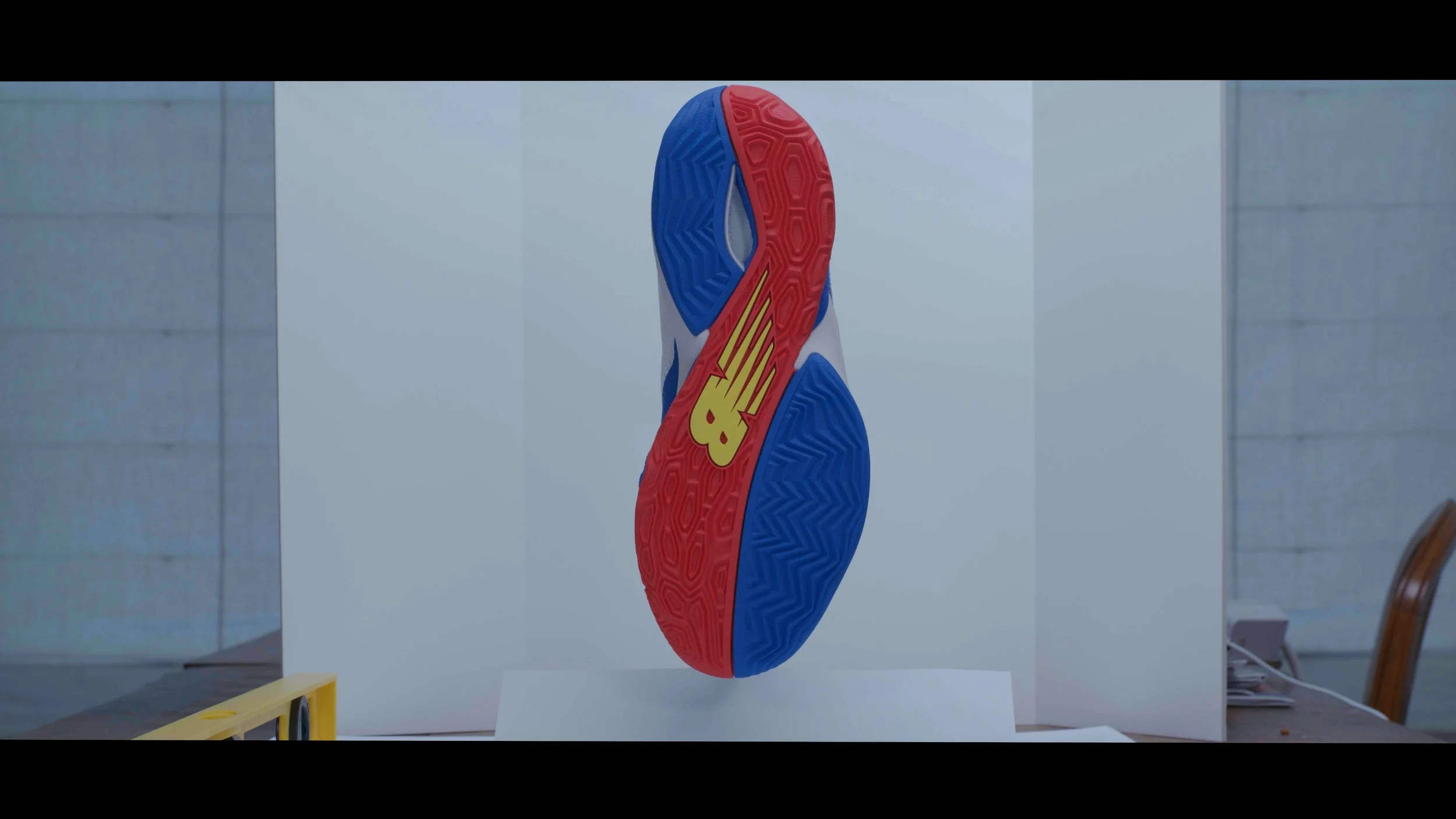 Colorful sneaker sole with a yellow logo, displayed vertically on a white background.