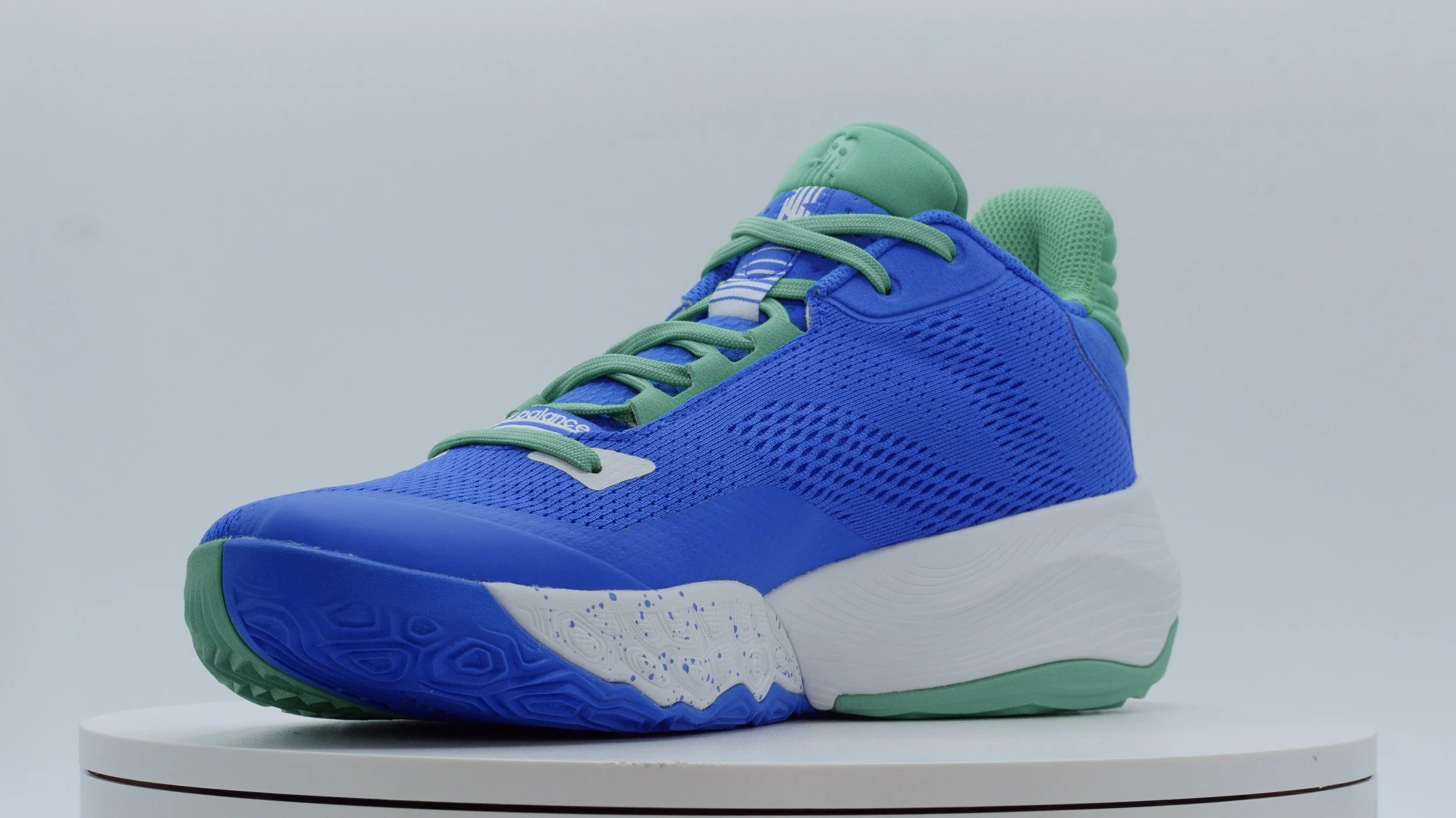 Colorful athletic shoe with blue upper, green accents, and a white sole on display.