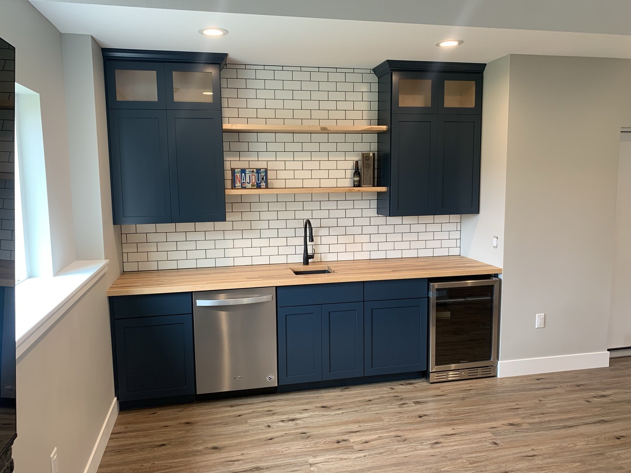 Basement wet bar with blue cabinets and subway tile