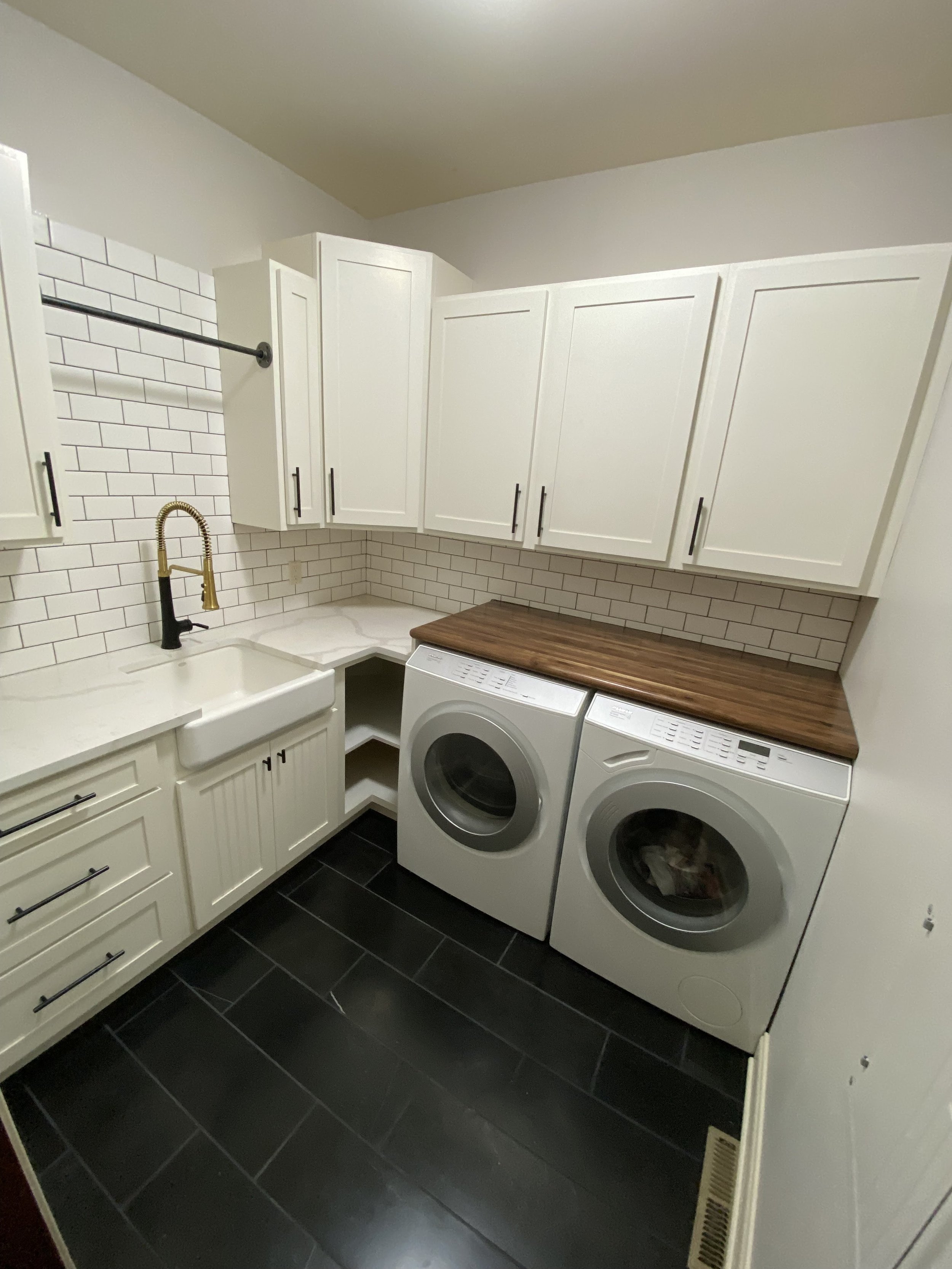 White laundry room with black tile floor