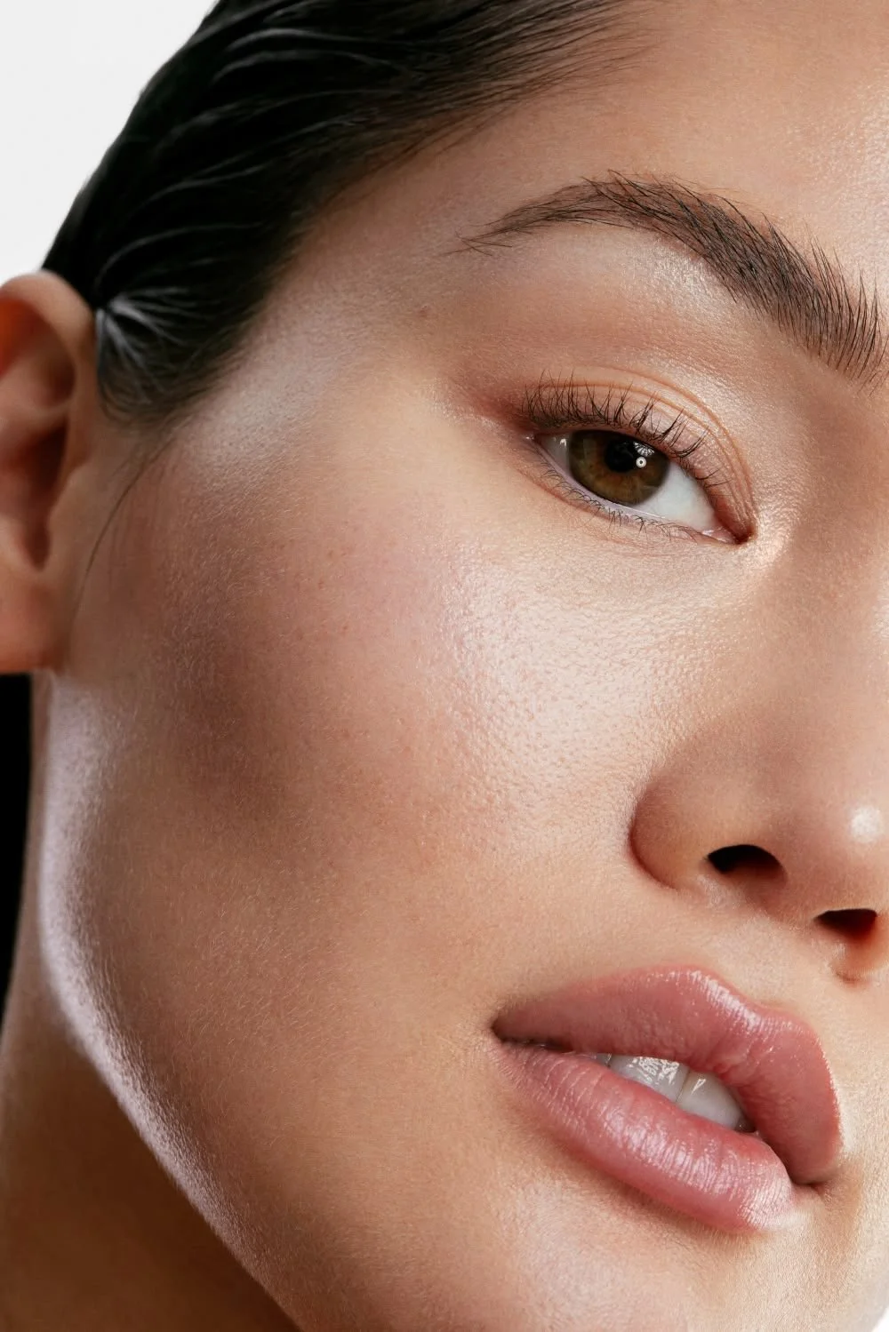 Close-up of a woman's face focusing on her eye, cheek, and lips, with smooth skin and natural makeup.