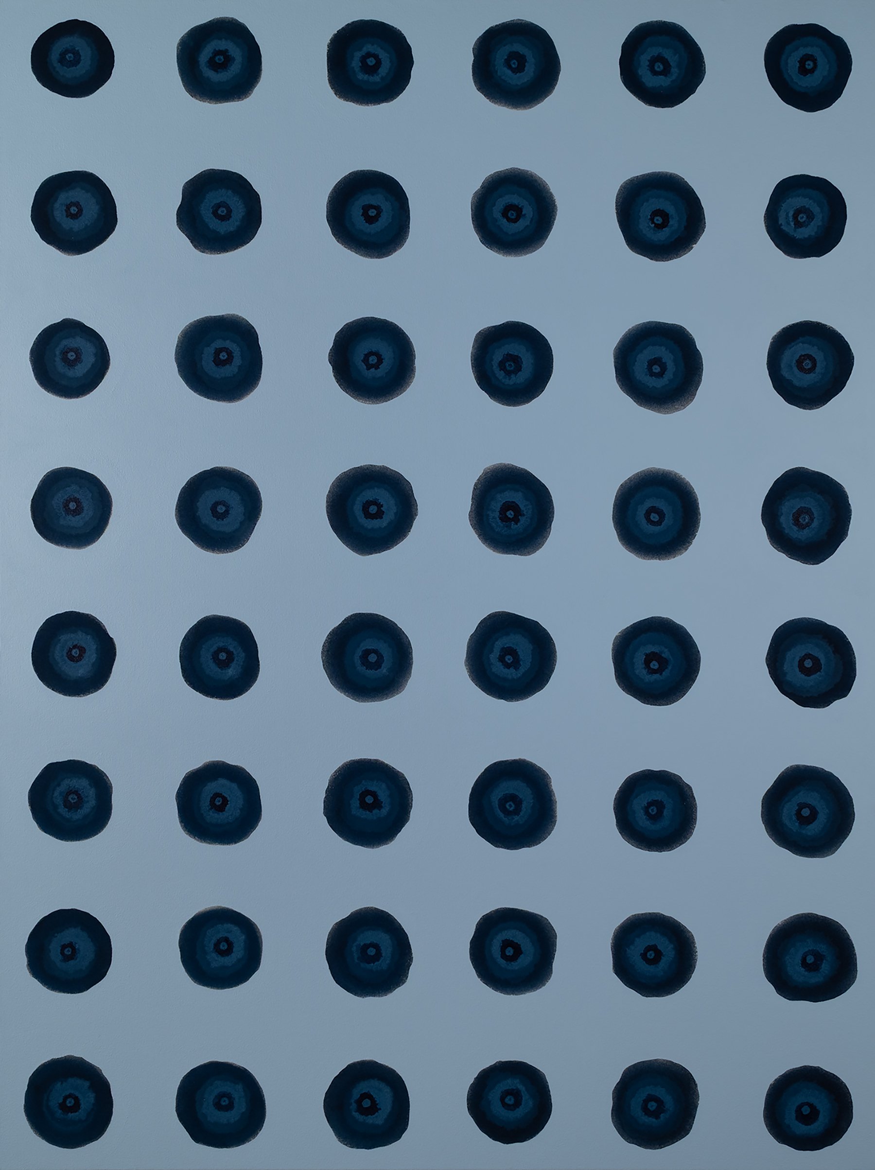 A pattern of numerous blue and black circles arranged in rows on a light blue background.