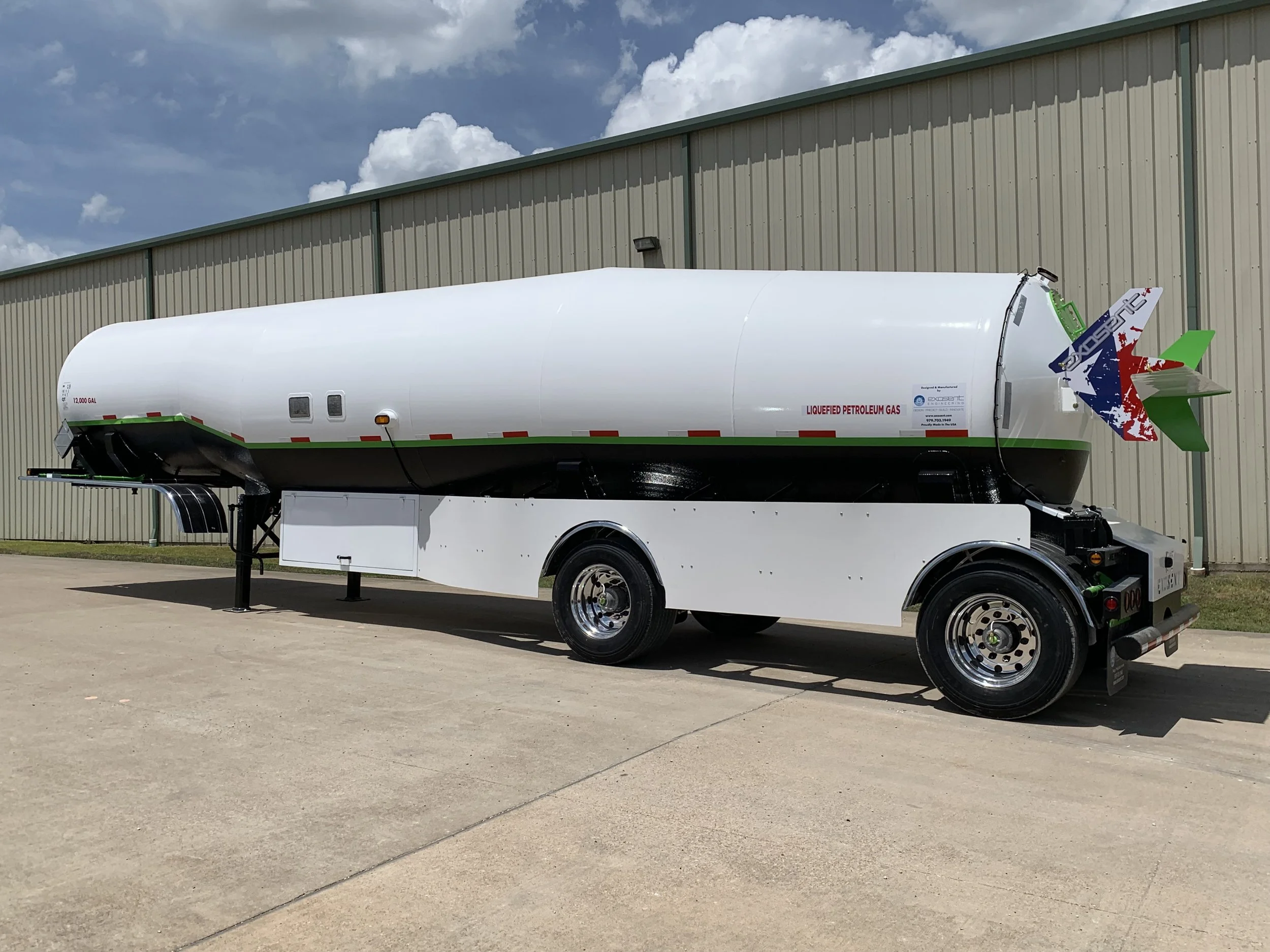 Large liquid petroleum gas tank mounted on a white trailer parked outside near a beige industrial building.