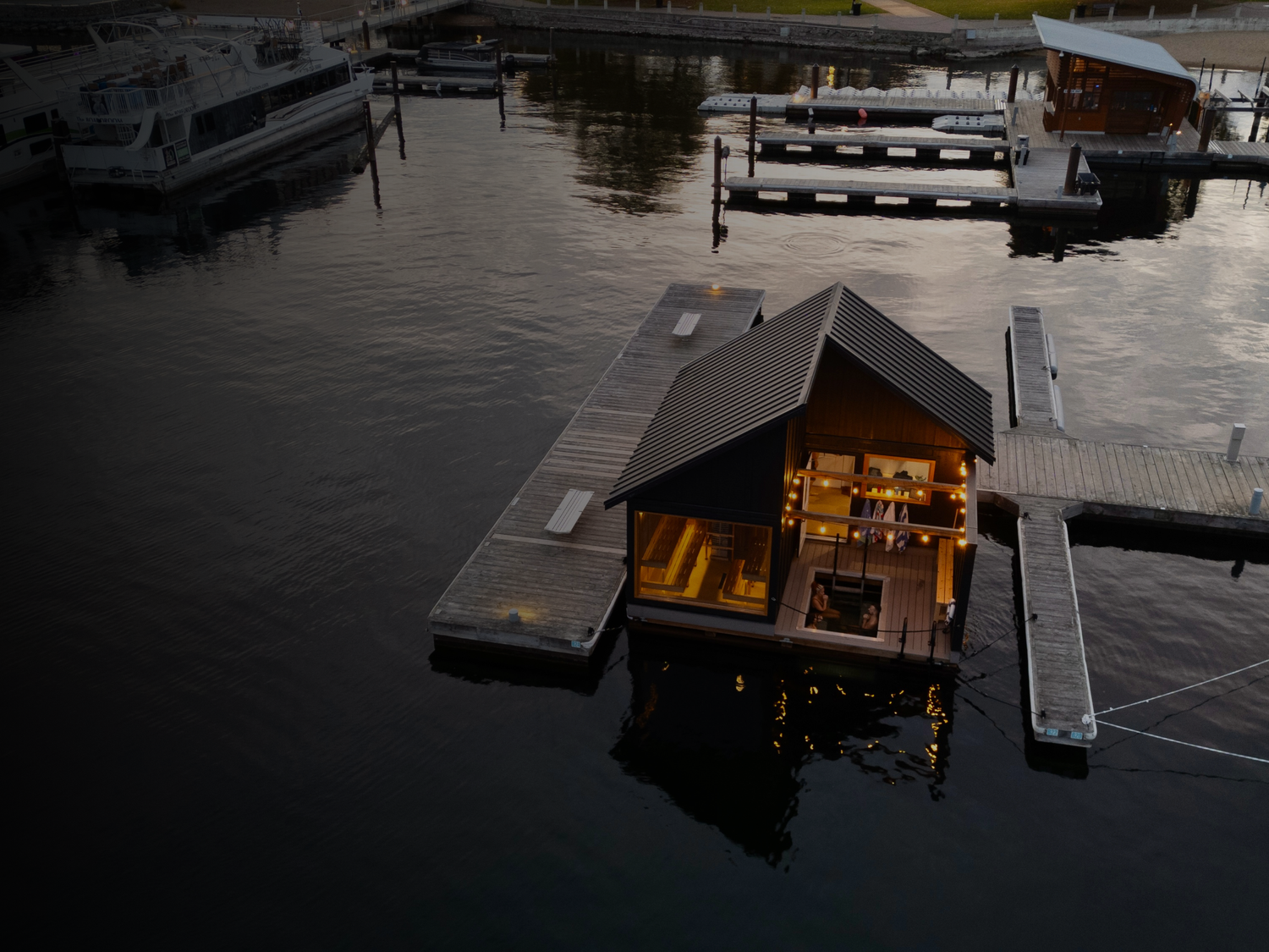 Löyly’s gabled floating sauna glows at dusk in Kelowna’s marina.