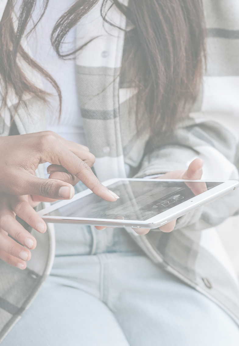 Person using a white smartphone with a reflective screen, wearing a plaid jacket and jeans.