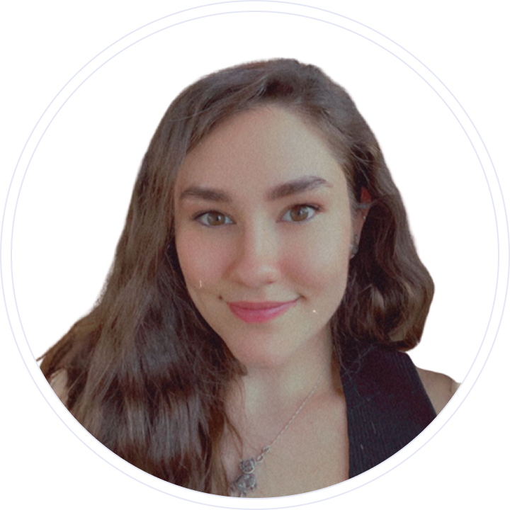 Close-up of a young woman with long brunette hair, smiling, wearing a black top and a silver necklace.