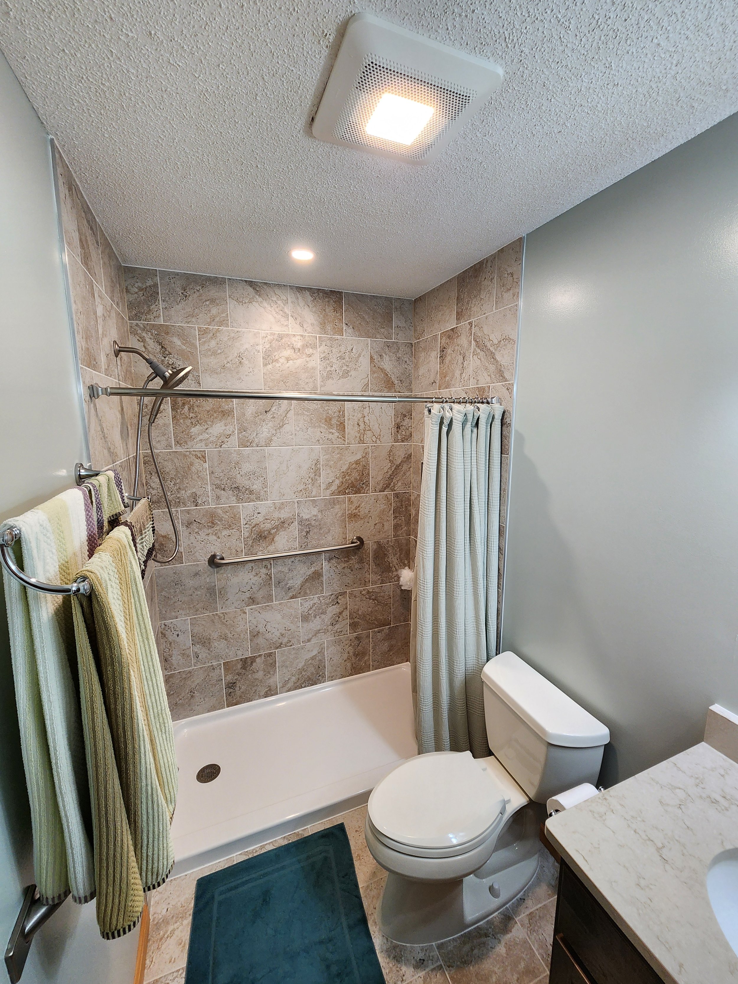 Bathroom with shower, toilet, towels, and sink.