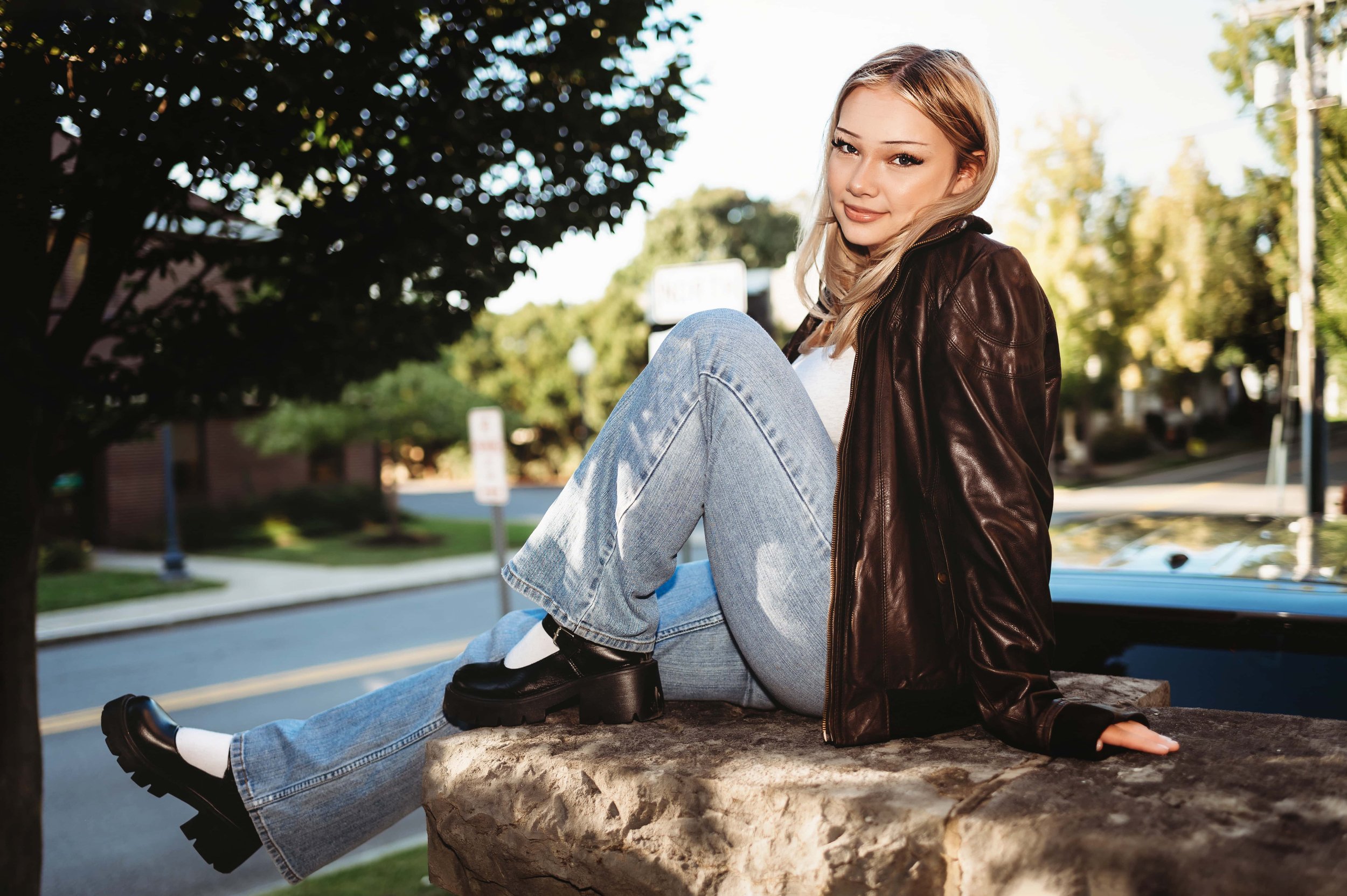 senior girl sitting on a wall downtown