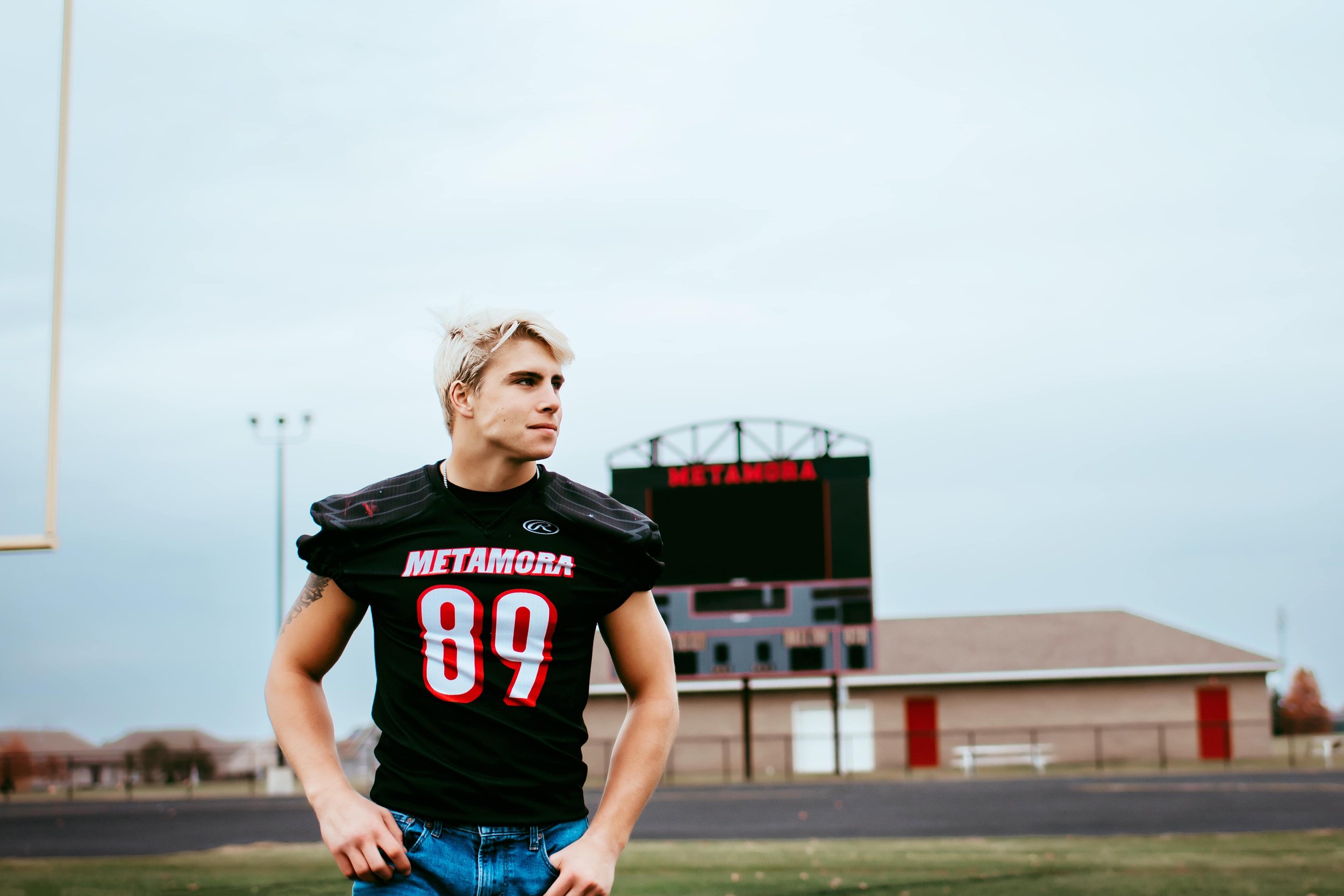 football player on field during senior pictures in the fall
