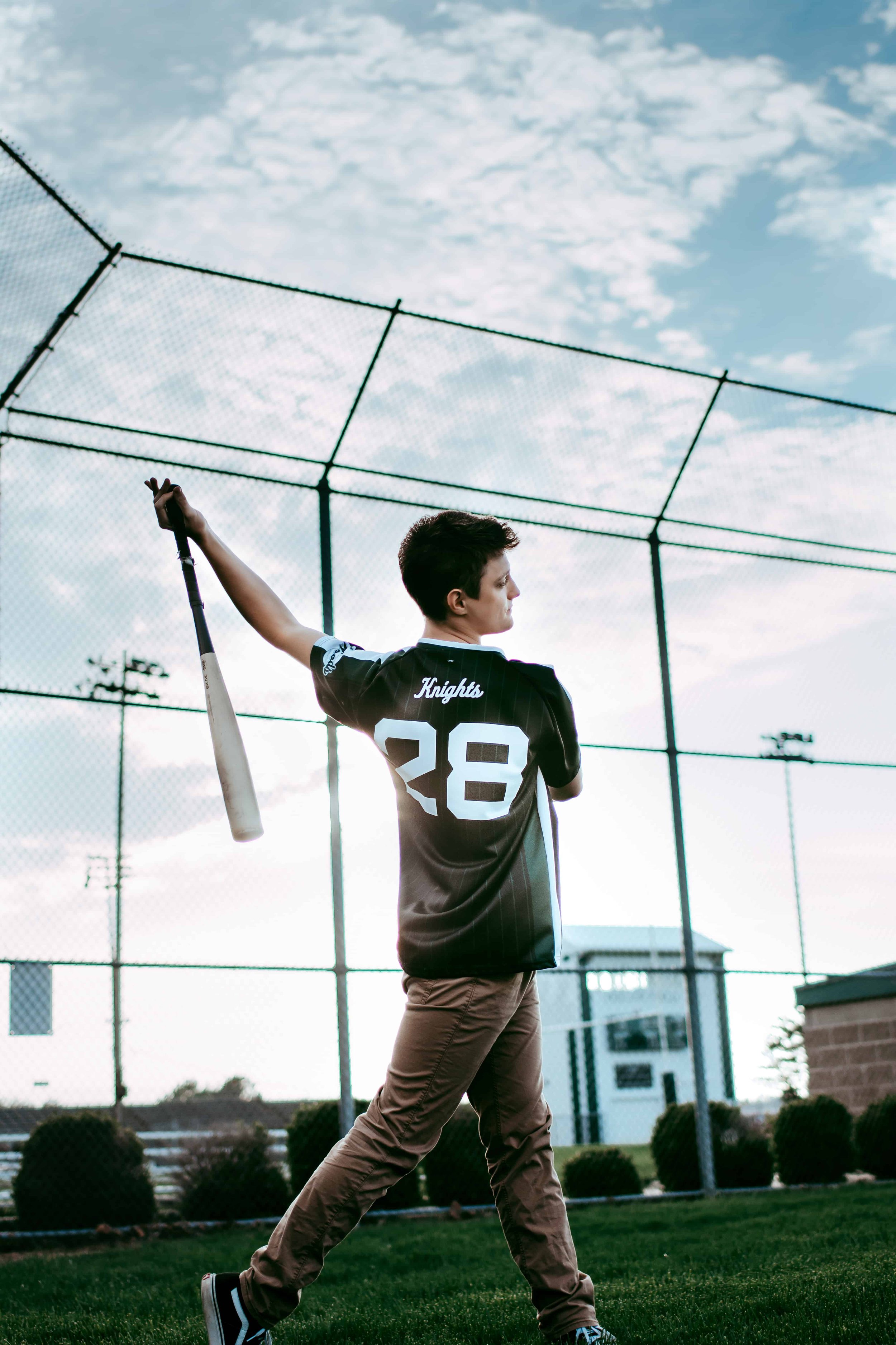 baseball player swinging bat during senior pictures