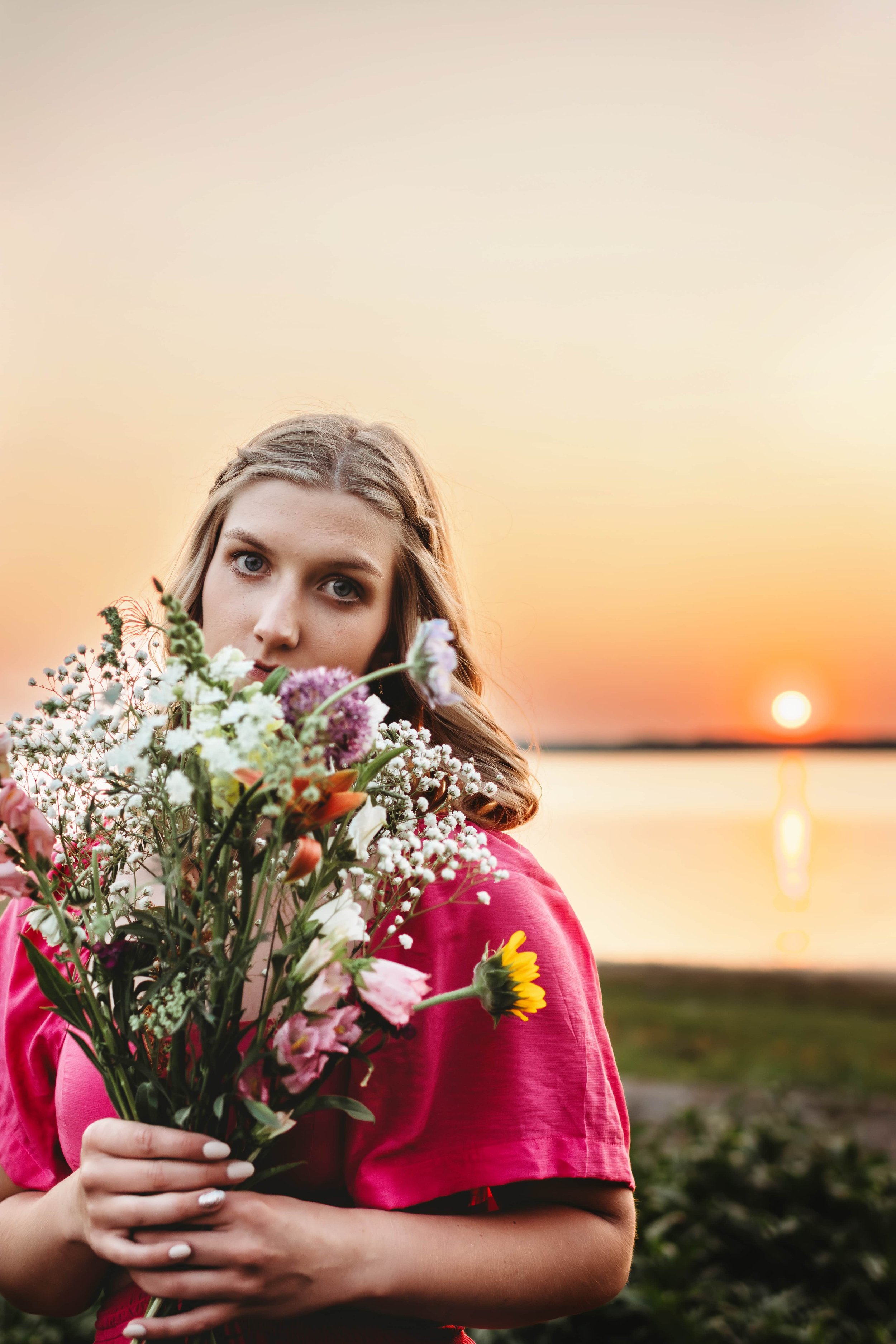 senior girl holding flowers at sunset