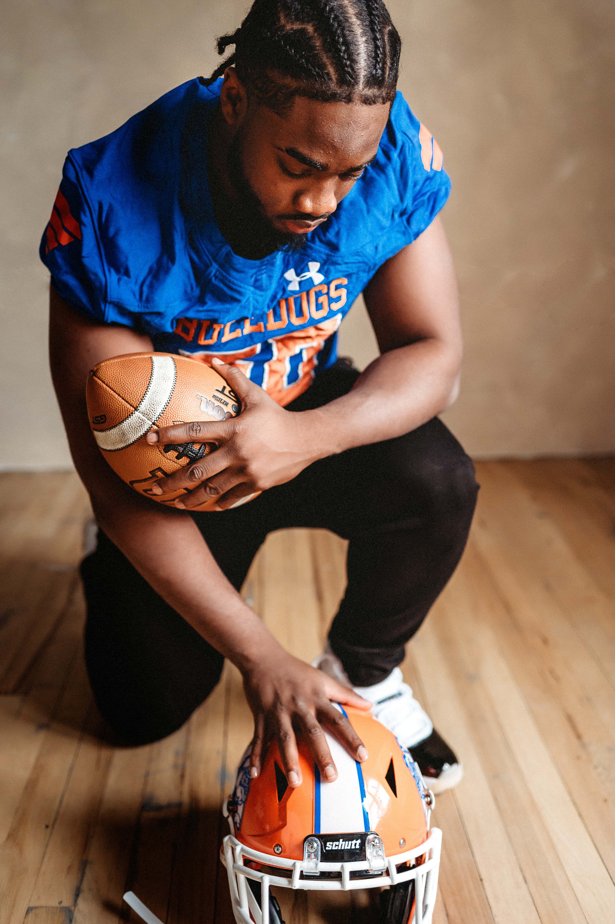 football player posing in photography studio with football and helmet