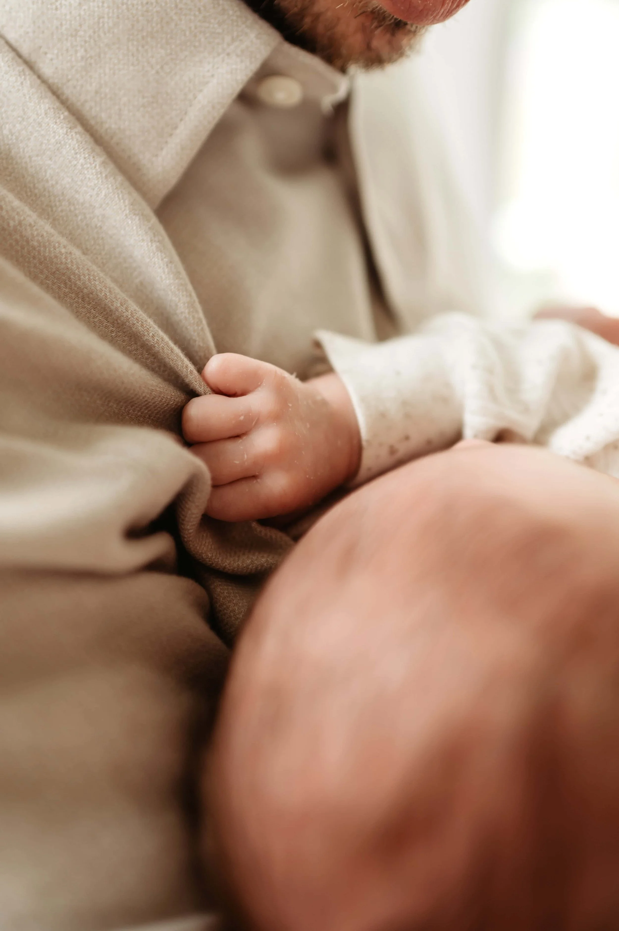 baby holding dad's shirt during newborn session