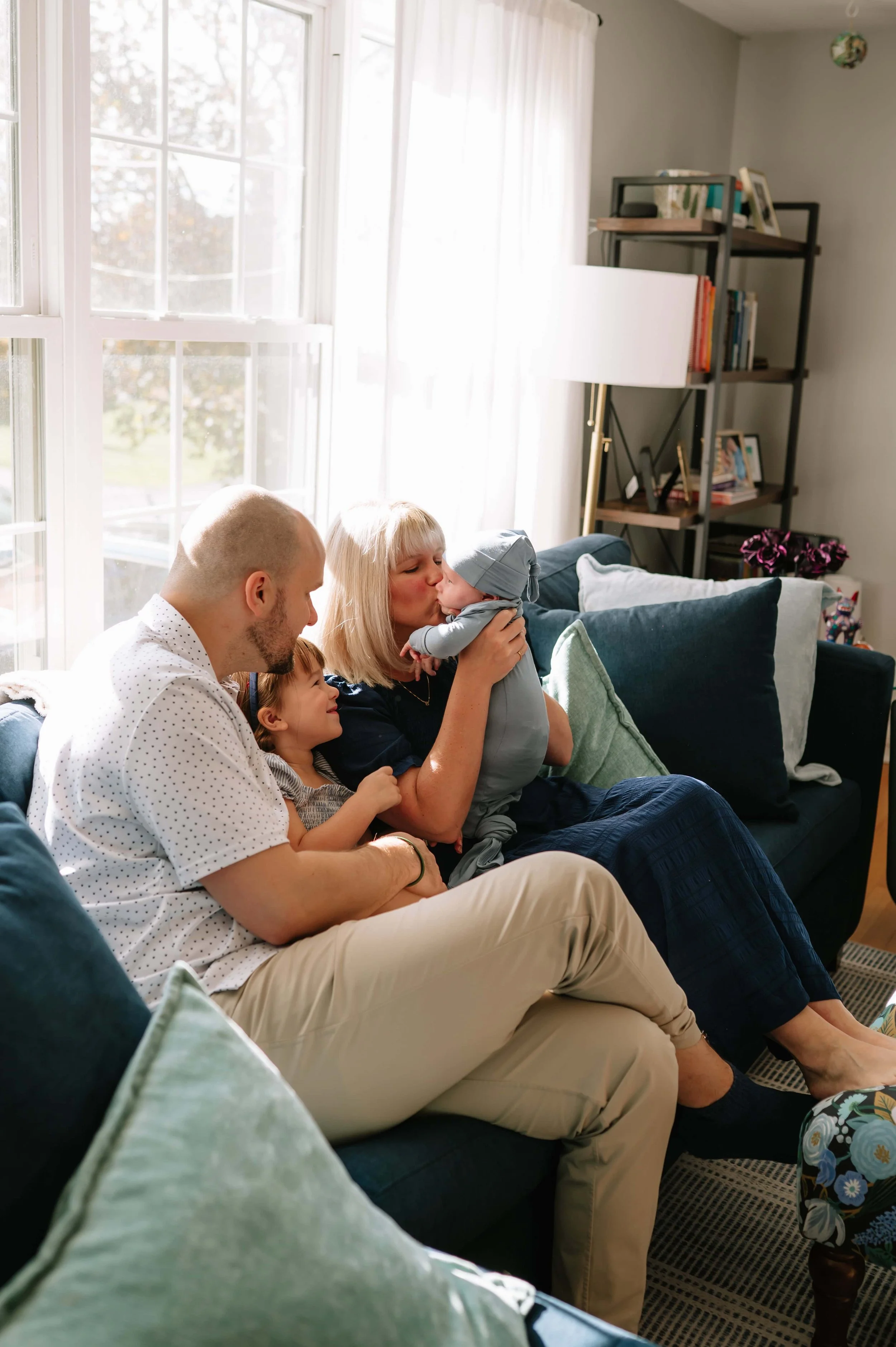 family cuddling on couch during newborn photos
