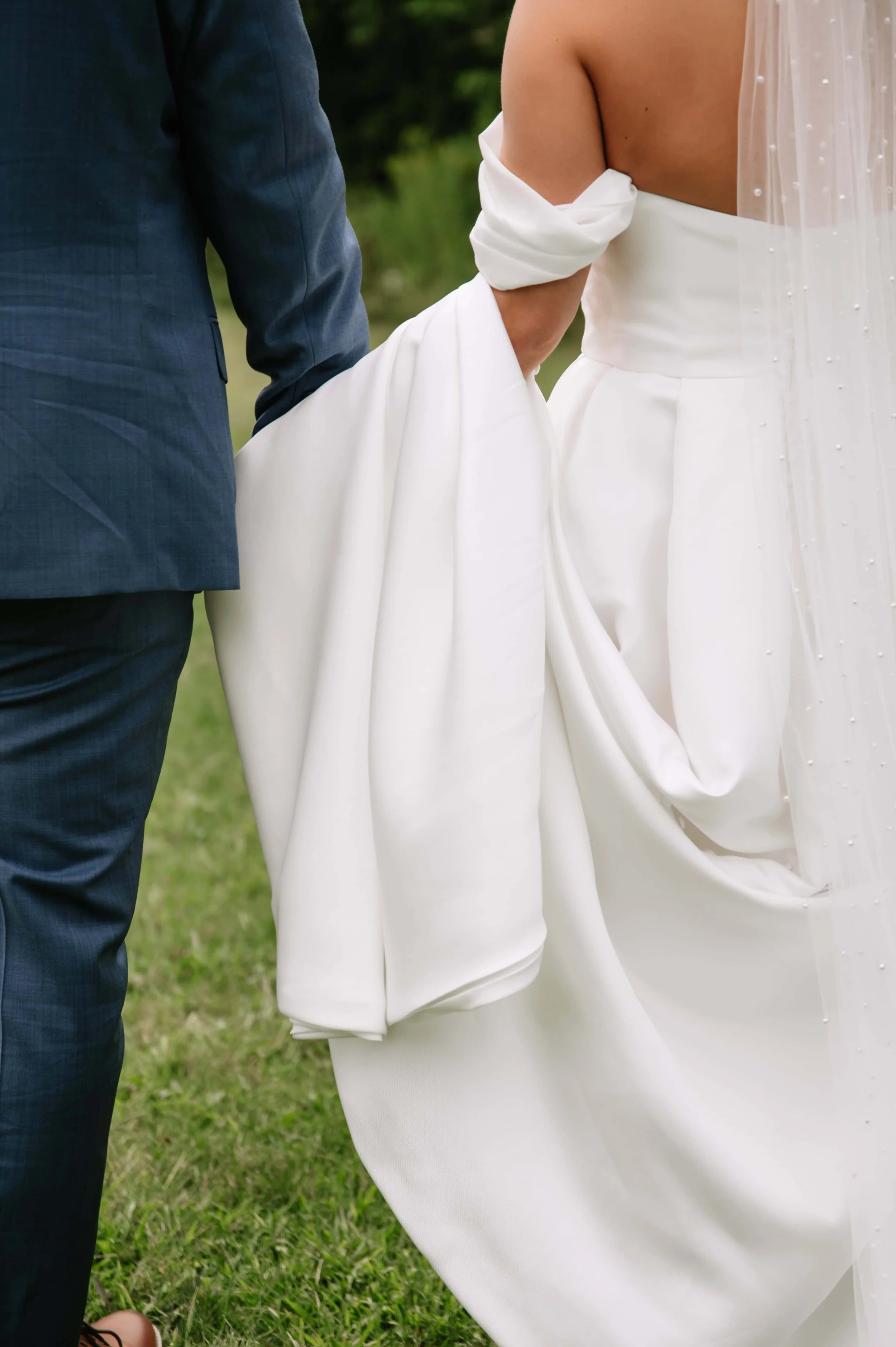 groom carrying bride's dress