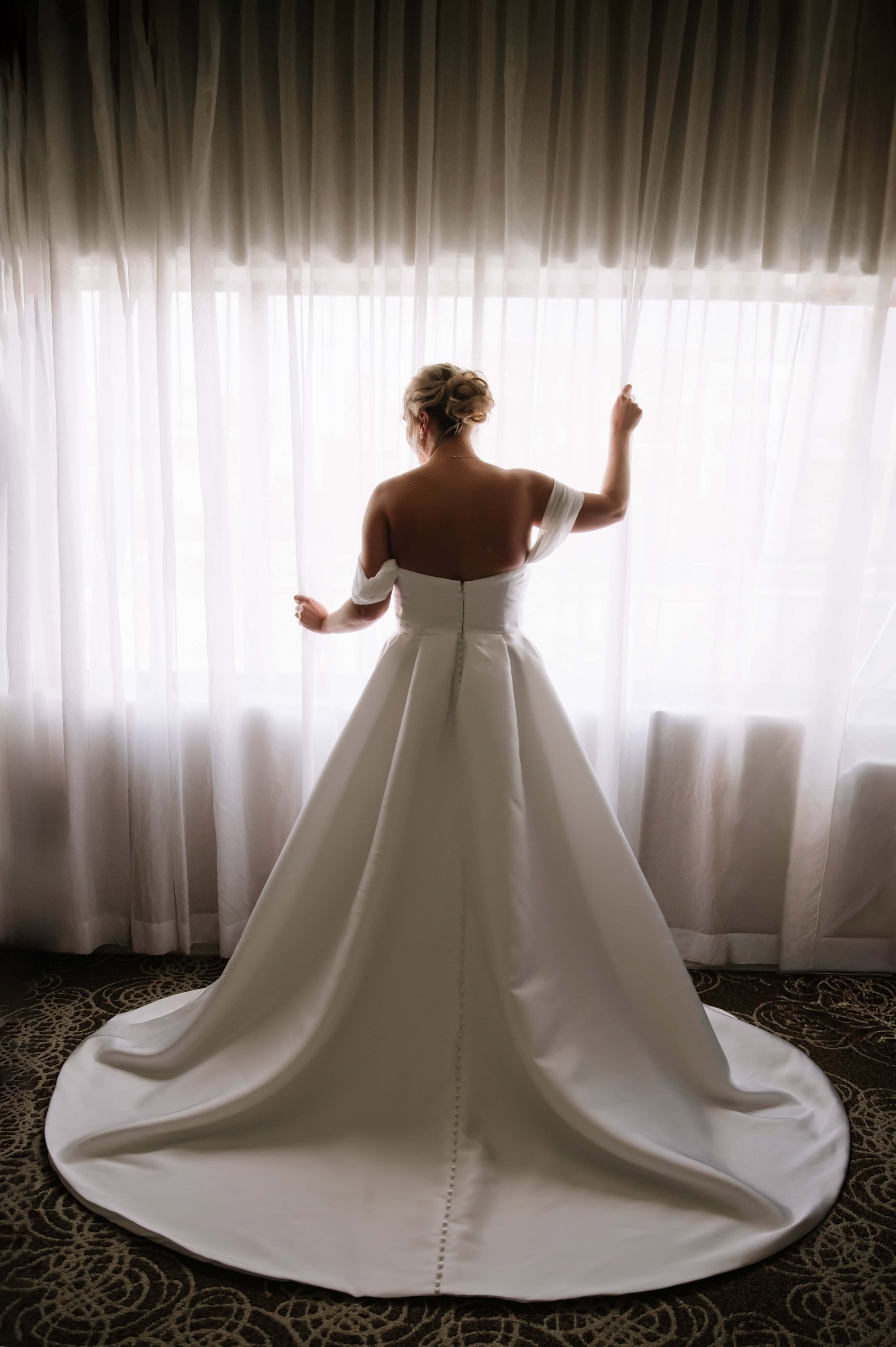 bride standing in window for bridal portraits