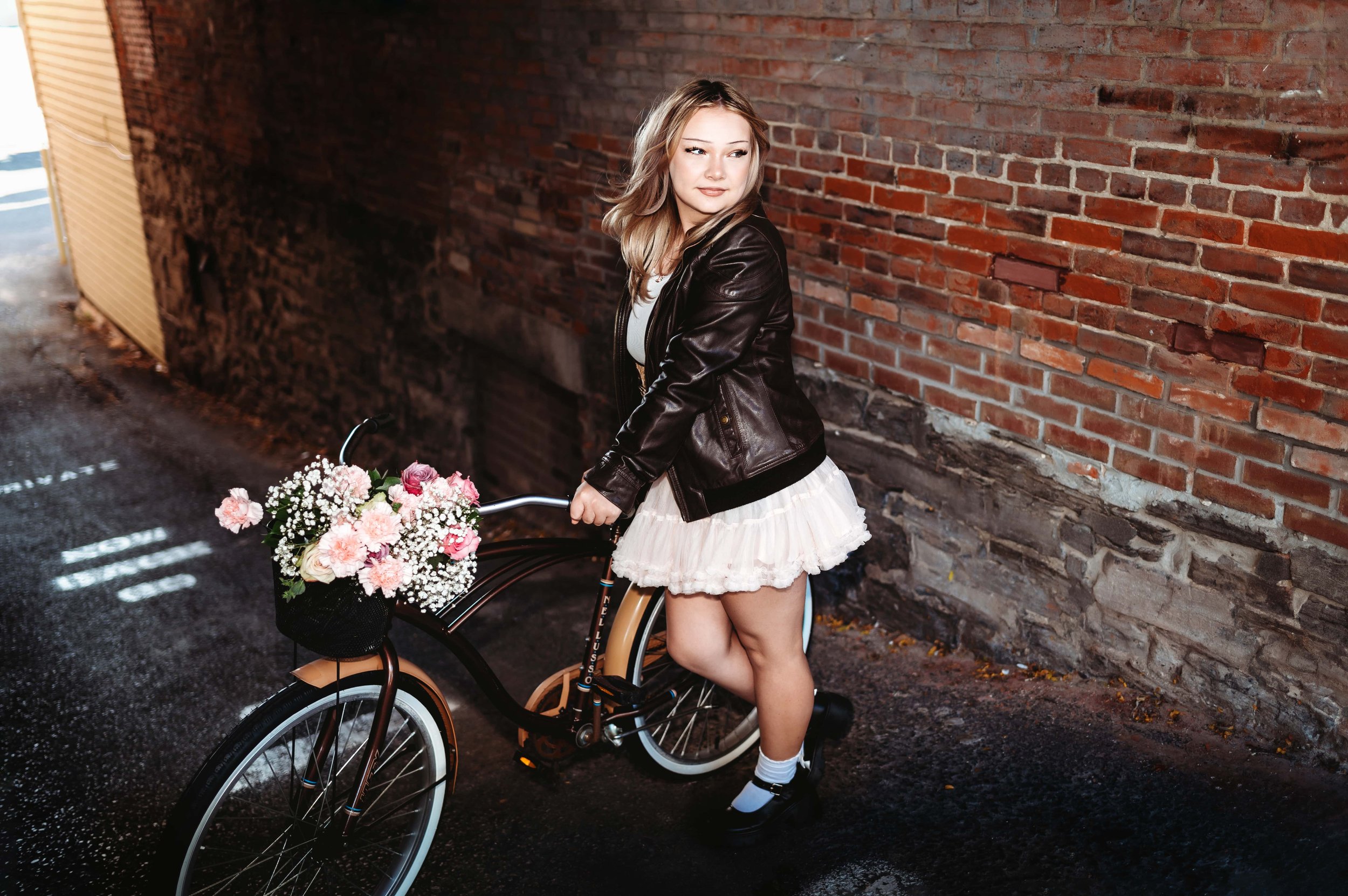 girl holding her bike filled with flowers during senior portraits