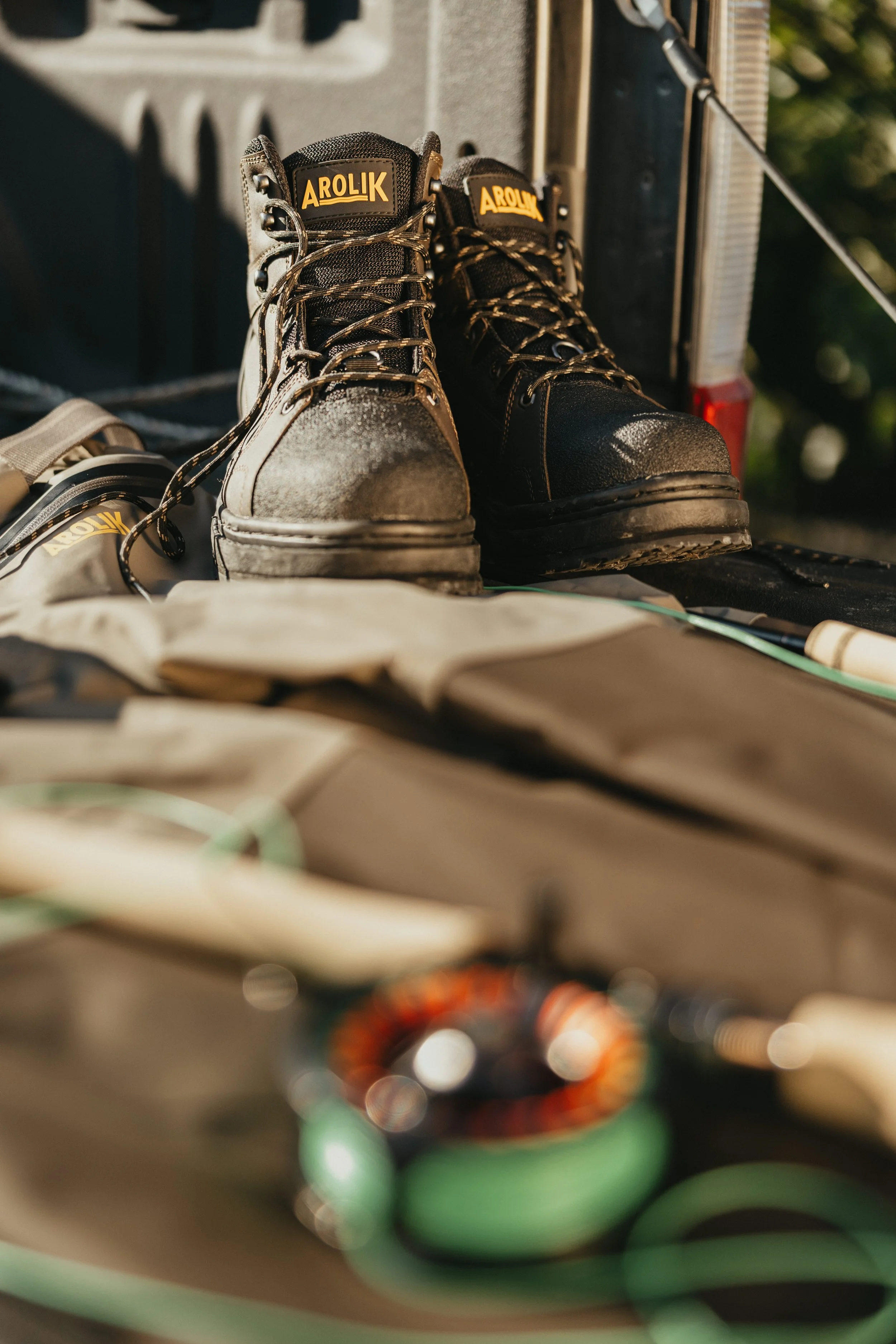 Product-focused image of Arolik wading boots and fishing gear arranged in warm natural light for commercial outdoor brand photography.