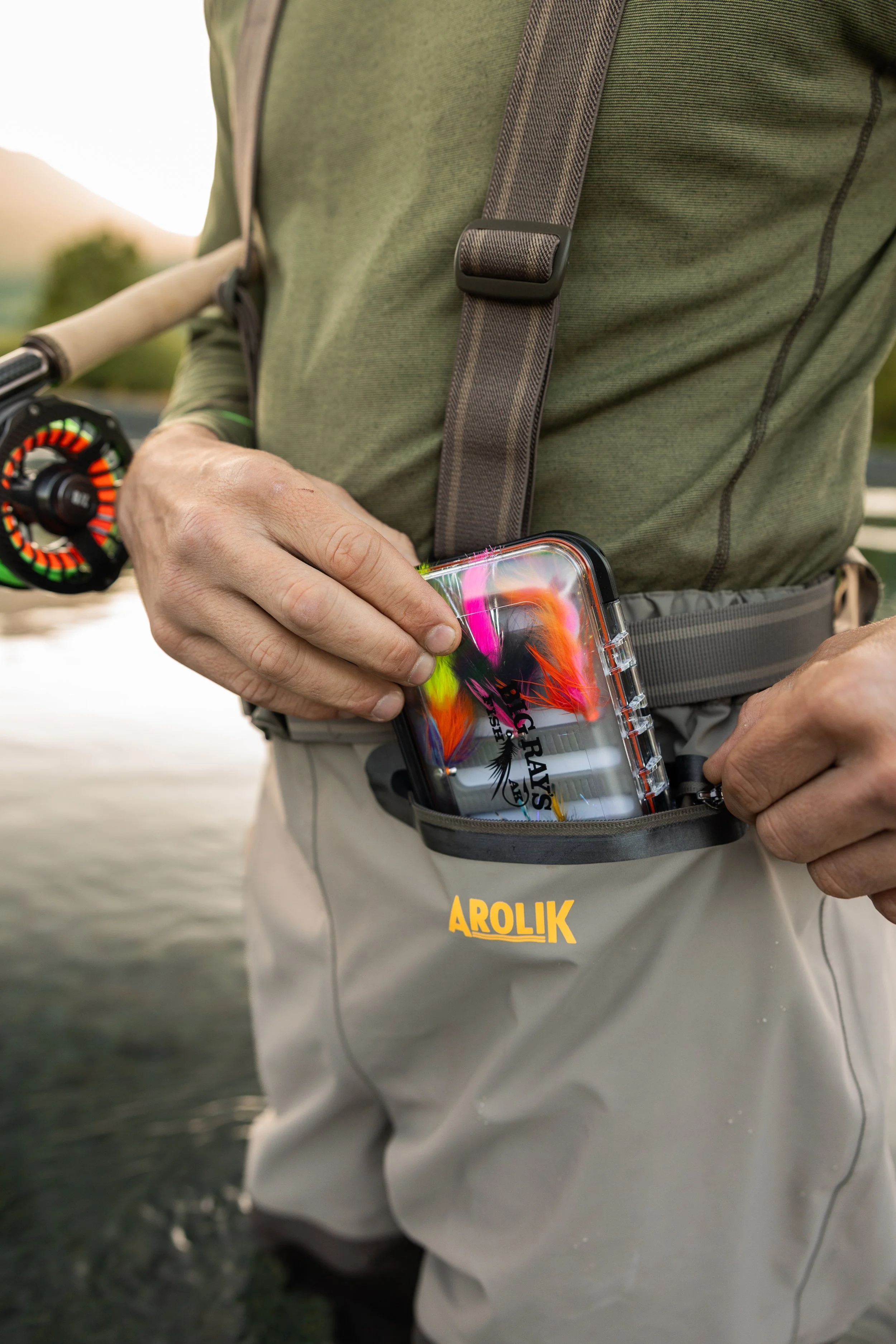 Close-up of Arolik waders pocket holding a fly fishing box with colorful flies.