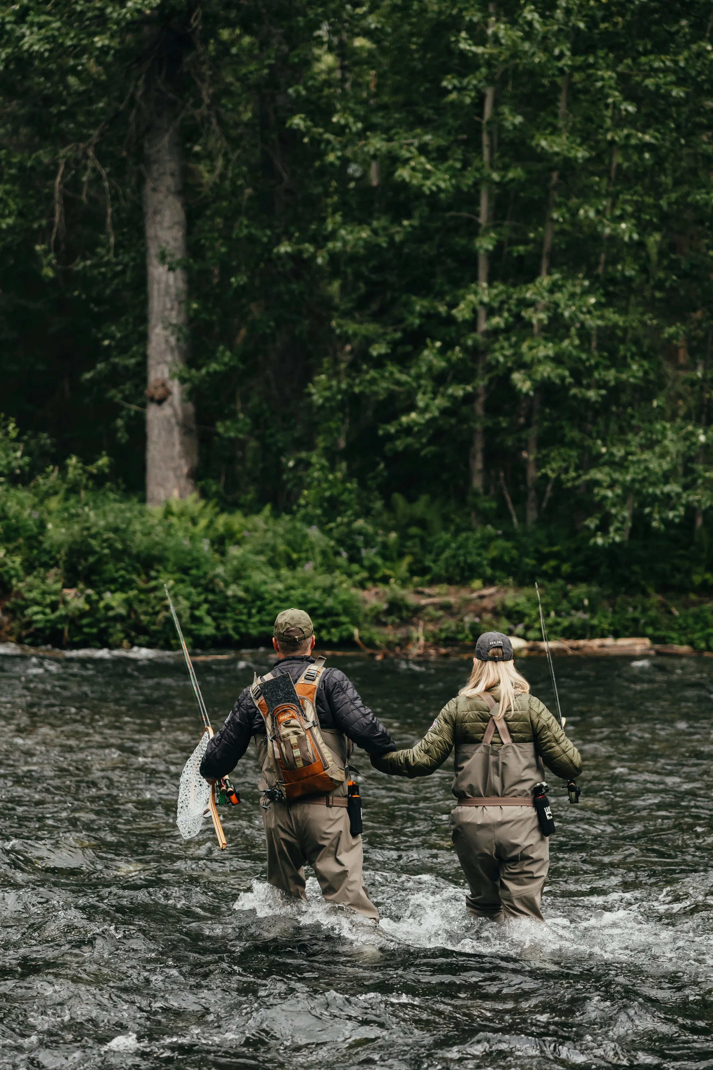 Two anglers walking through an Alaska river wearing Arolik waders during a fishing trip.