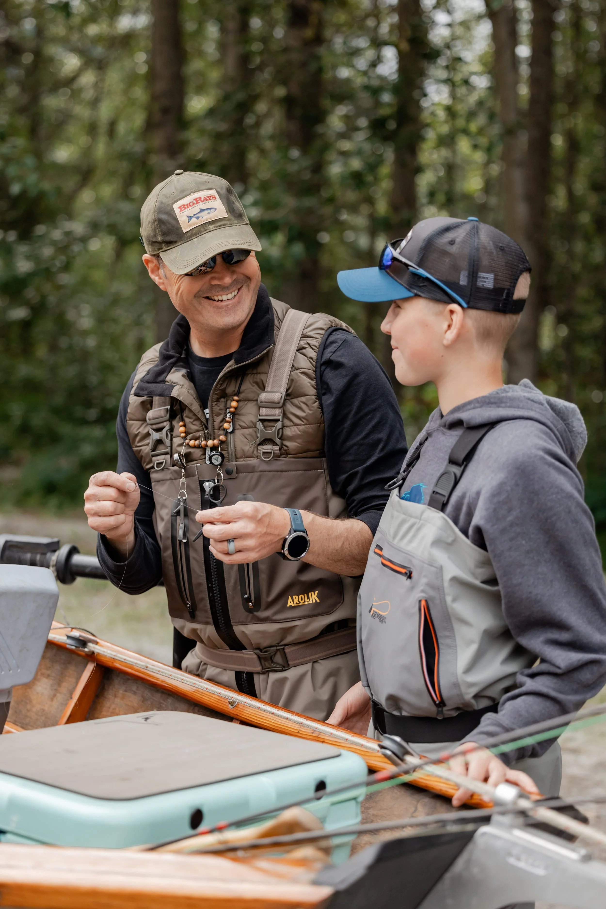 Man and boy preparing fishing gear while wearing Arolik waders beside a drift boat in Alaska.
