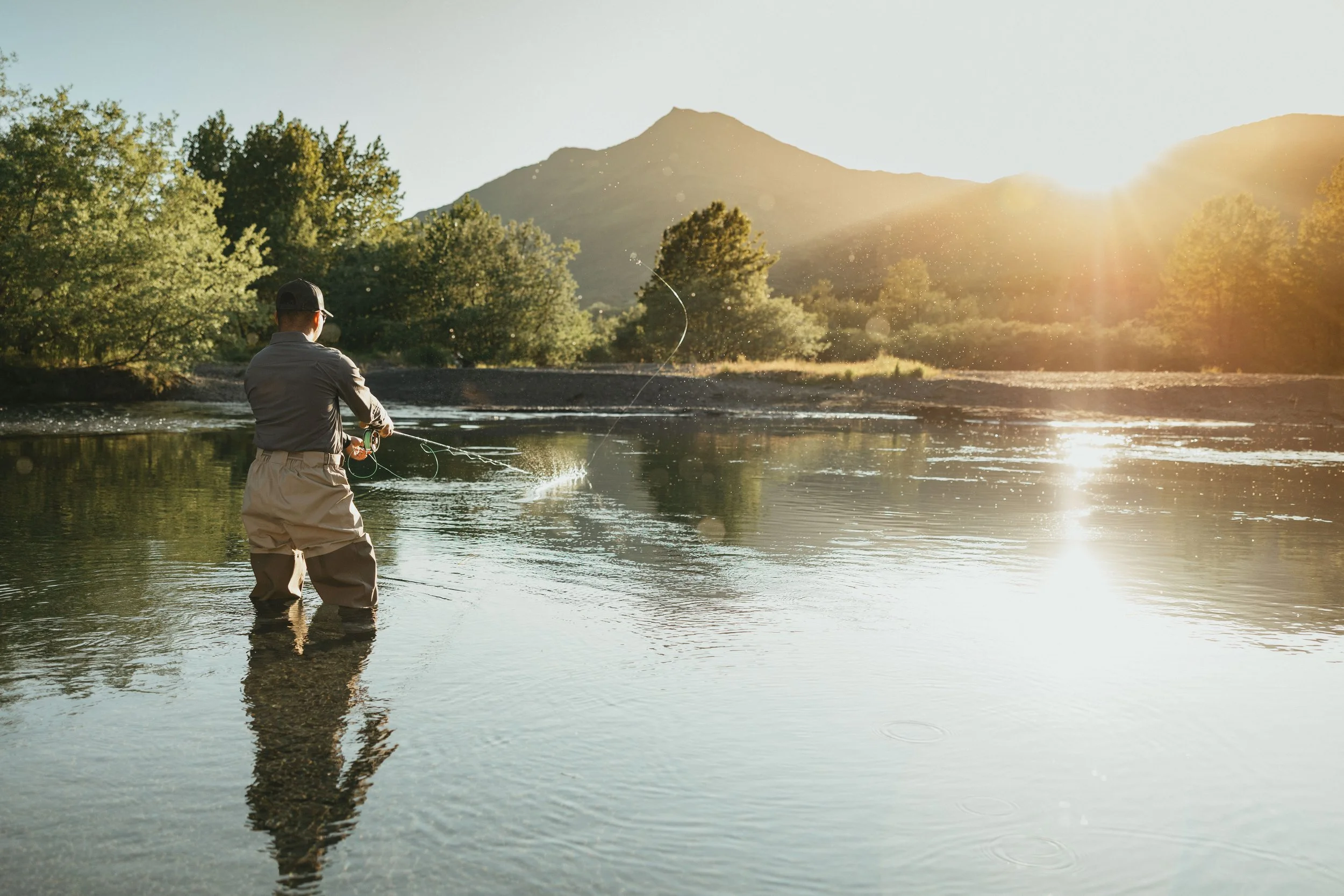 Fly fisherman casting in a calm Alaska river at sunset wearing Arolik waders.