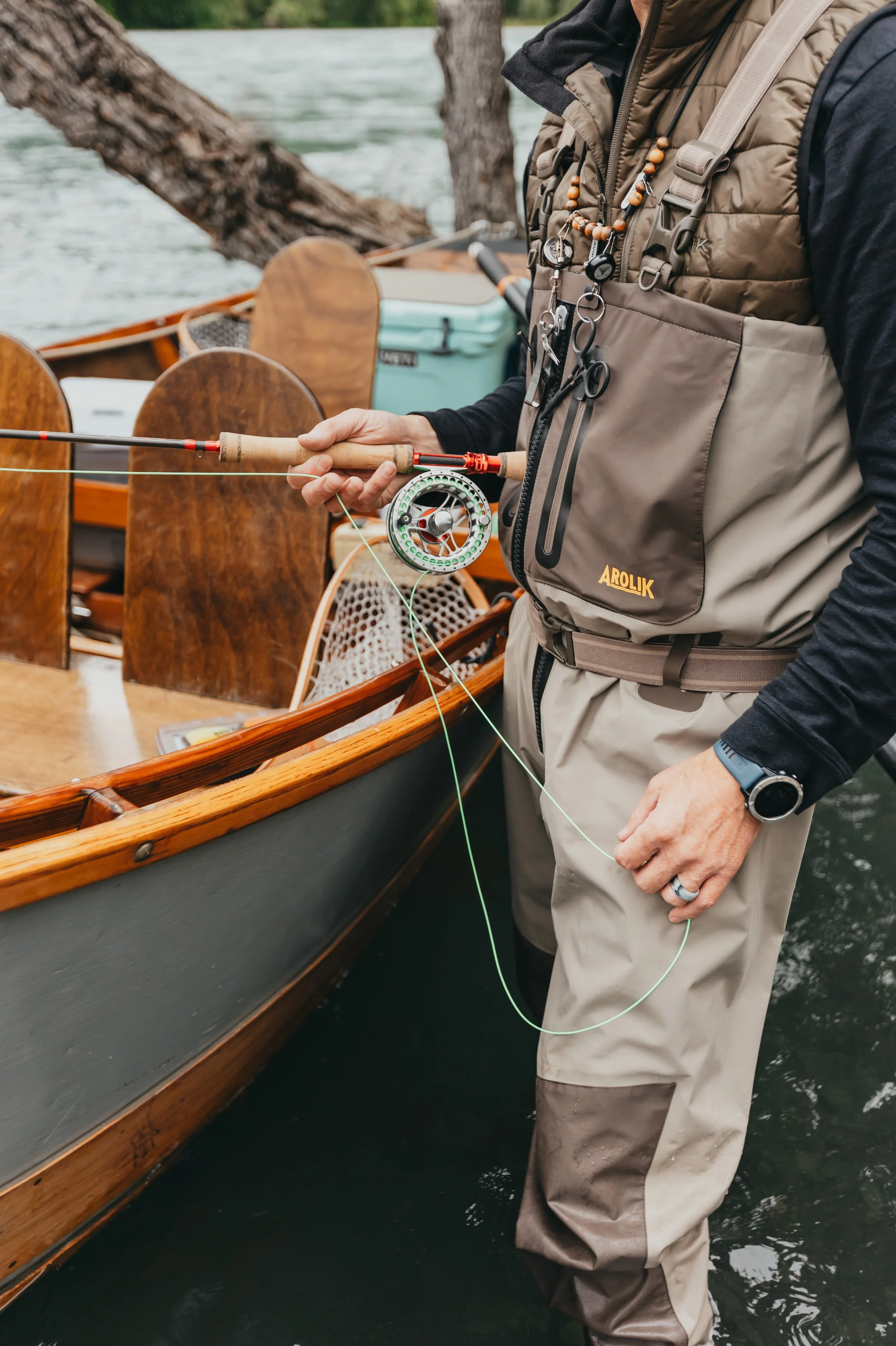 Arolik fishing waders worn beside a drift boat with fly rod and gear ready for use.