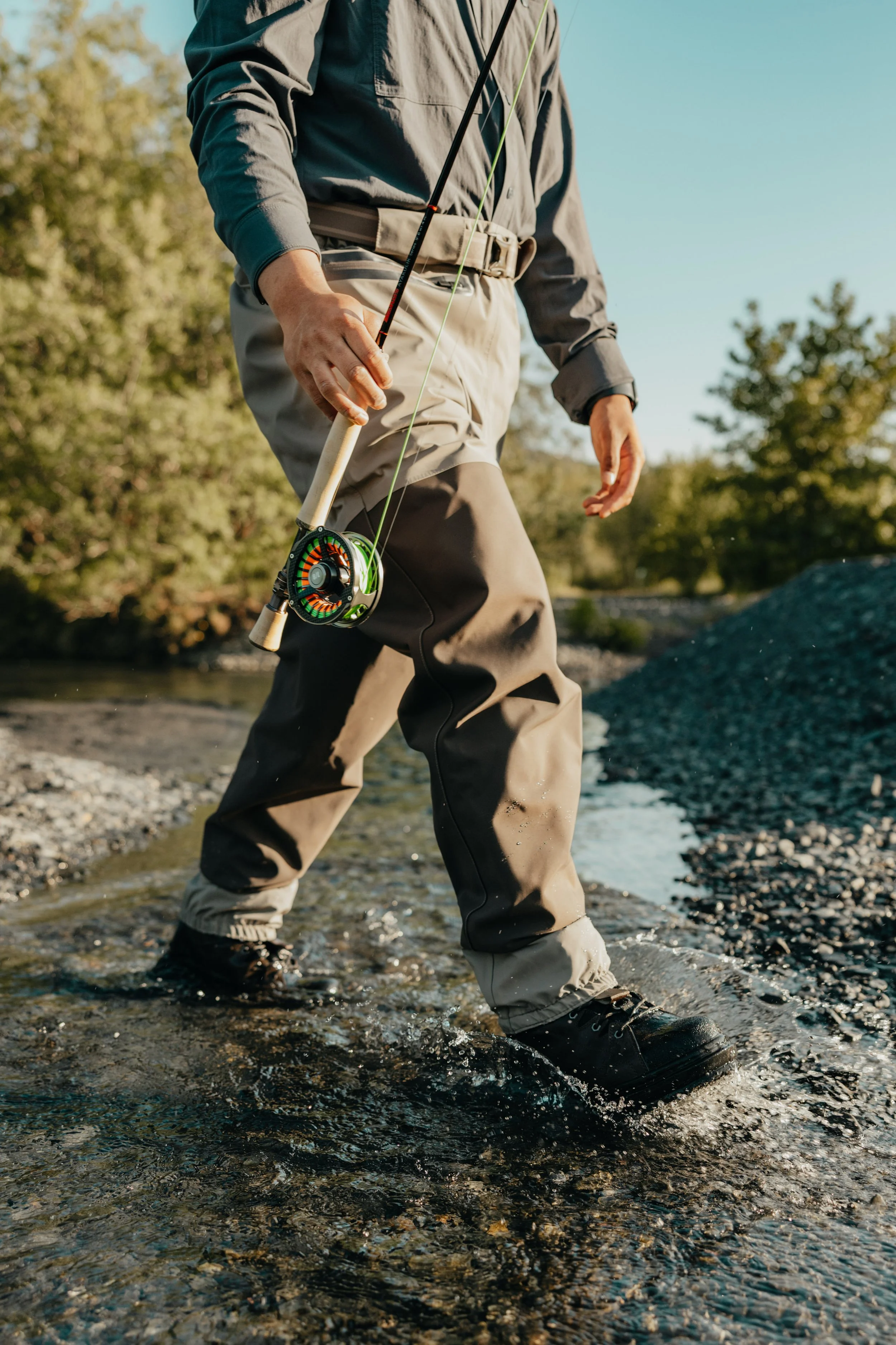 Angler walking through shallow river water in Arolik waders during outdoor fishing.