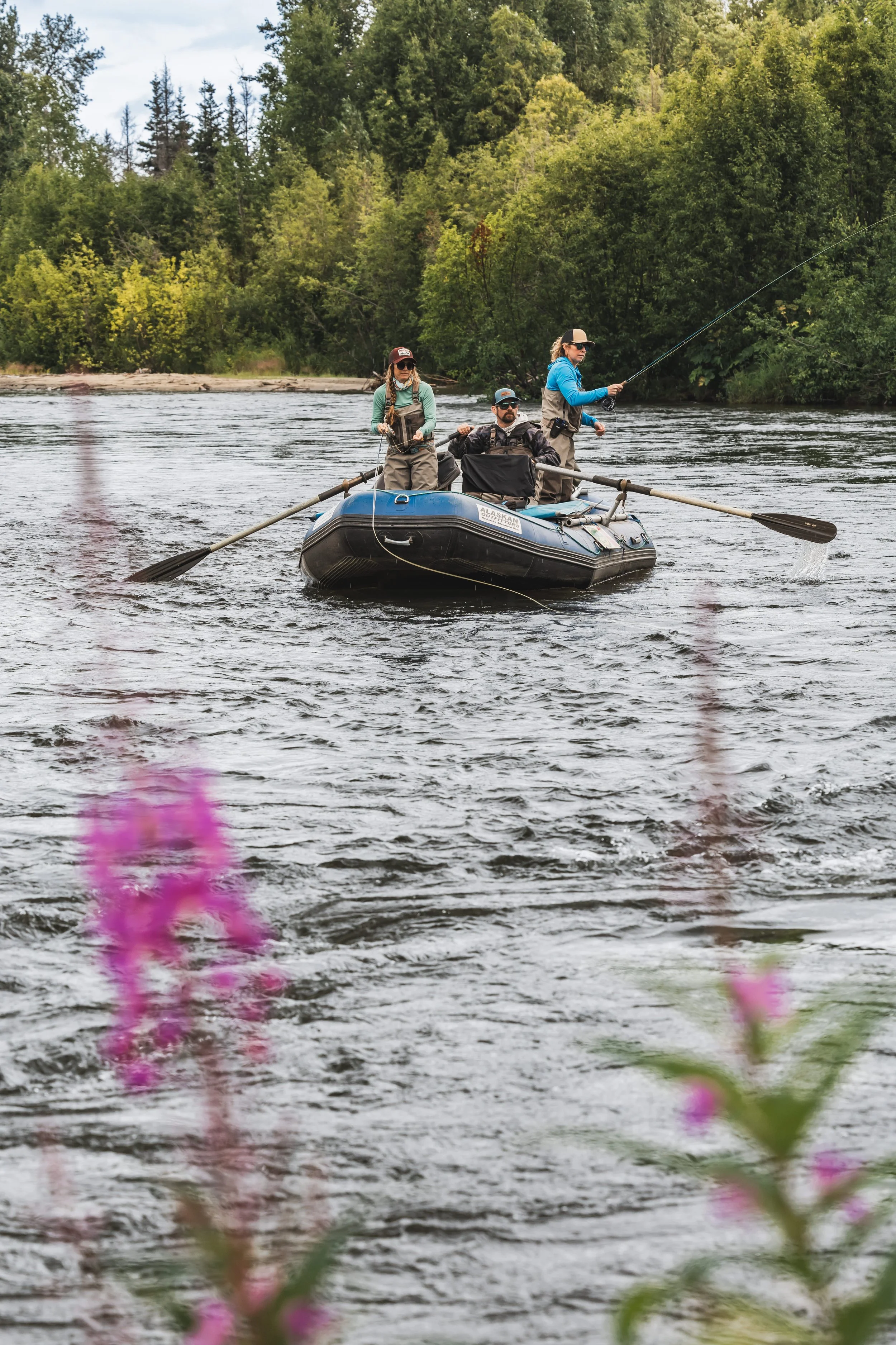 Group of anglers fishing from a drift boat on an Alaska river, showcasing Arolik waders in a real outdoor fishing environment.