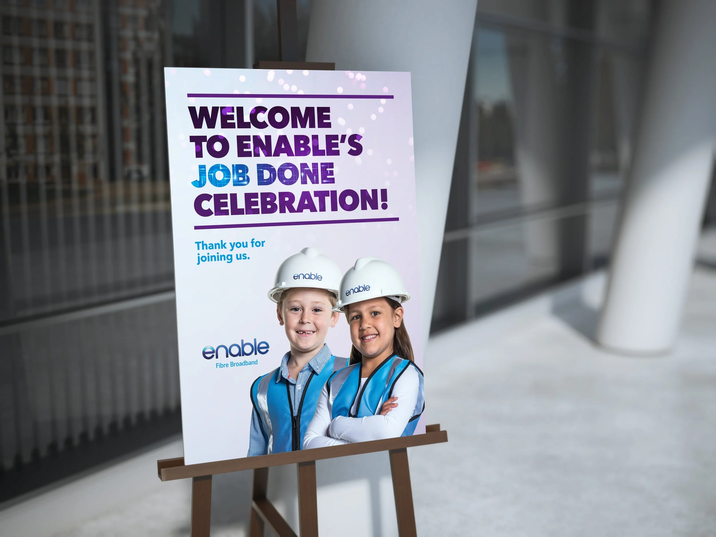 Sign with text 'Welcome to Enable’s Job Done Celebration' featuring two children in hard hats and vests.