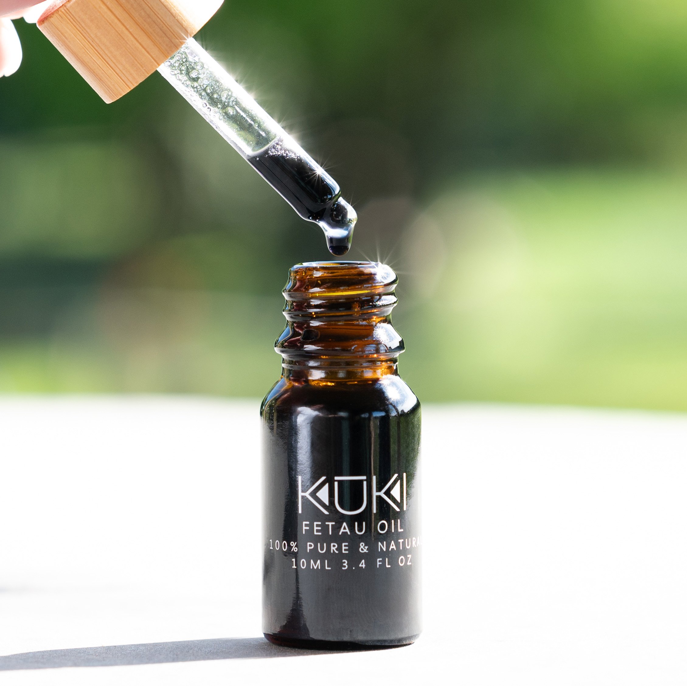 Bottle of Kuki Fetau oil with dropper dispensing oil