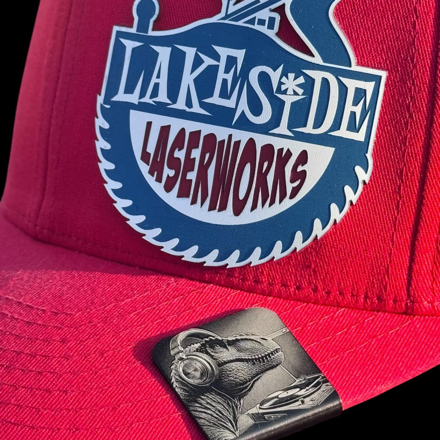 Red cap with a Lakeside Laserworks patch and a small dinosaur hat clip.
