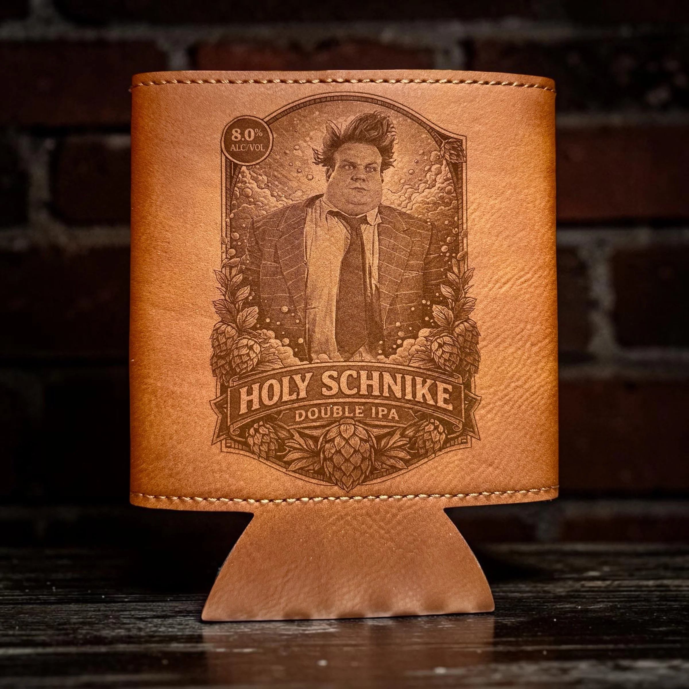 Leather beer koozie with a printed illustration of a man in a suit with spiked hair, surrounded by hops and the text "Holy Schnike Double IPA" and an alcohol content of 8.0% ABV.