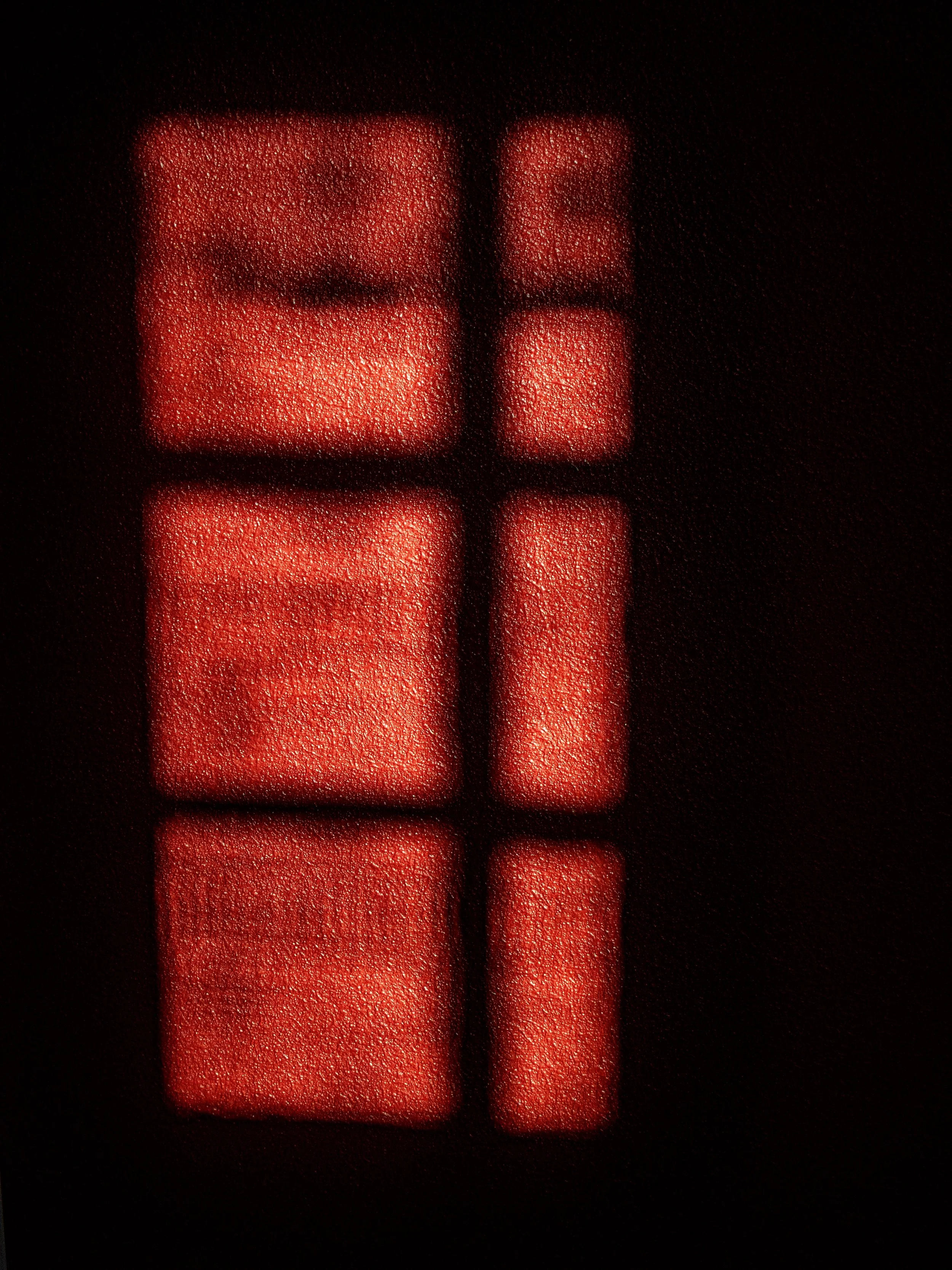 A close-up photo of several red pills with textured surfaces against a dark background.