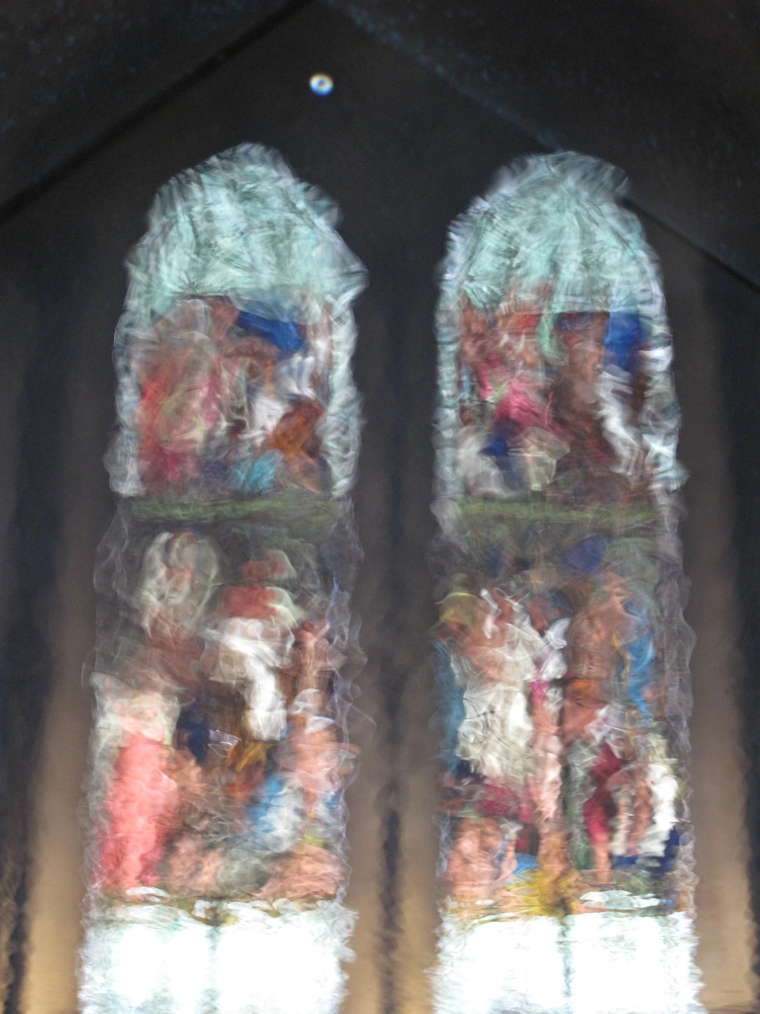 A blurry reflection of two pairs of colorful sneakers on a shiny dark floor.