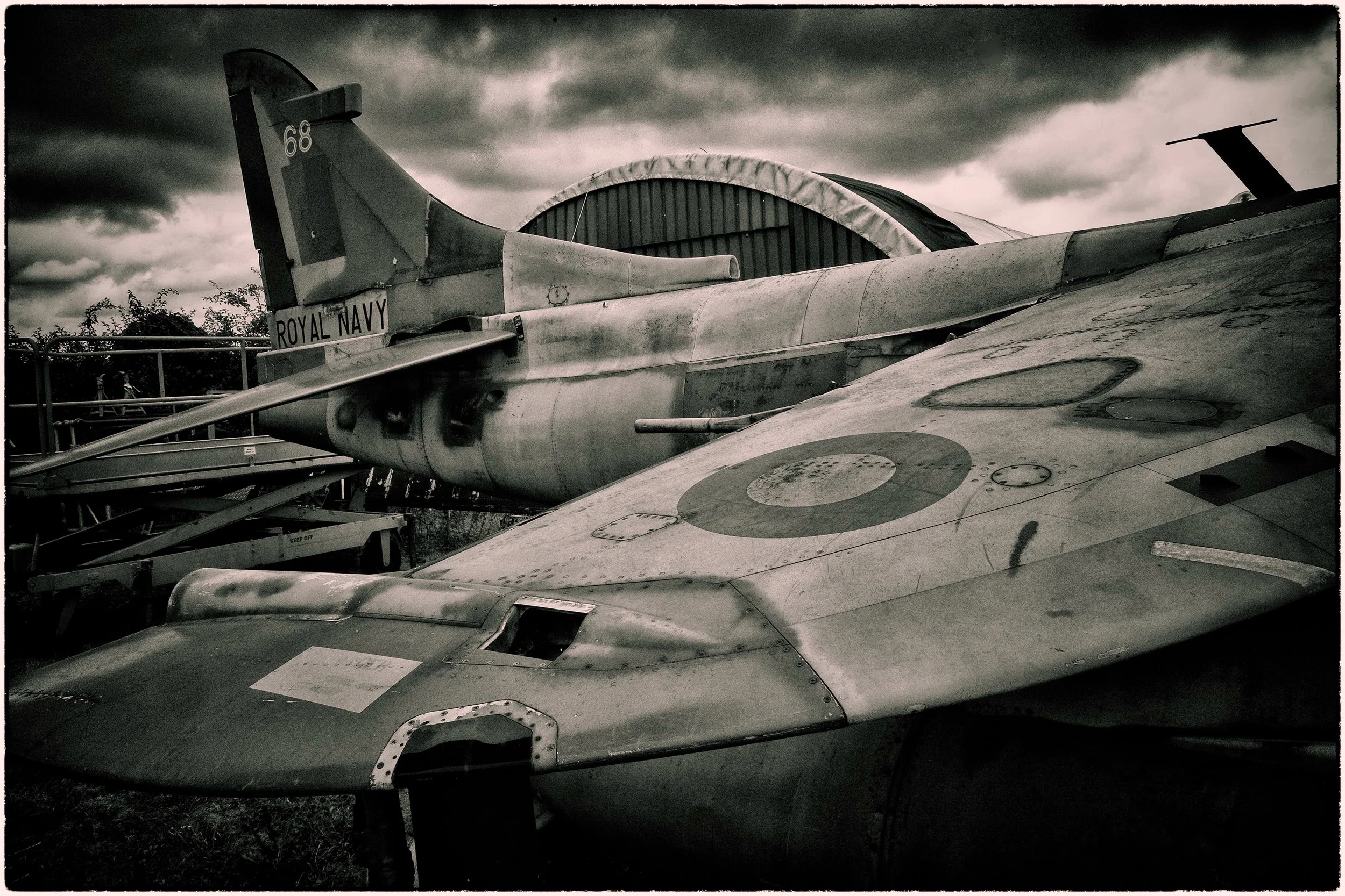 Vintage military jet aircraft on display outdoors with a cloudy sky overhead.
