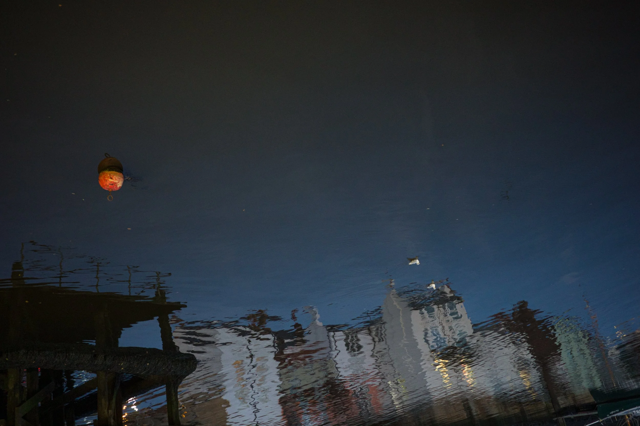 Reflections of boats and structures on water at night