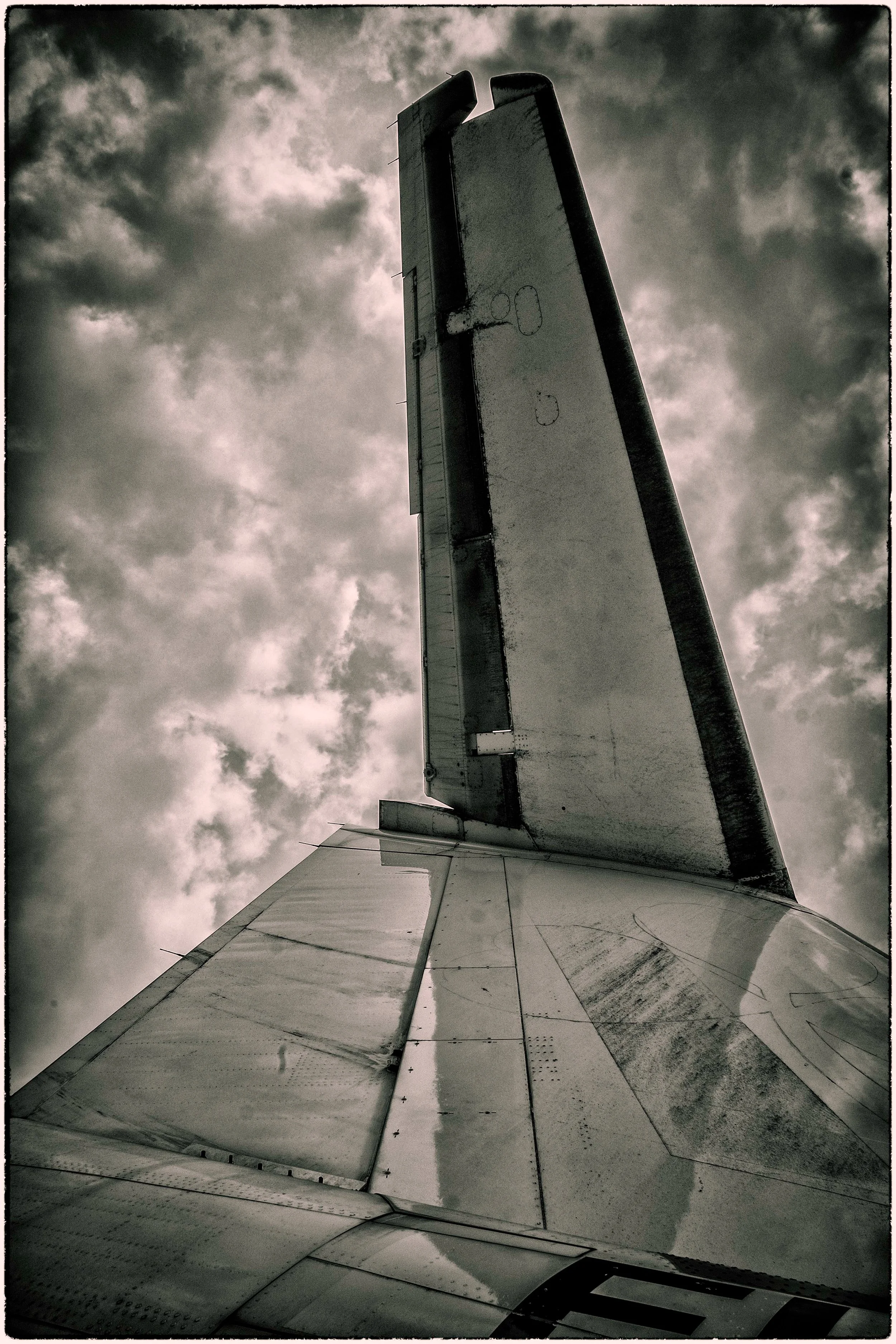 The image shows an upward view of an airplane's wing against a cloudy sky.