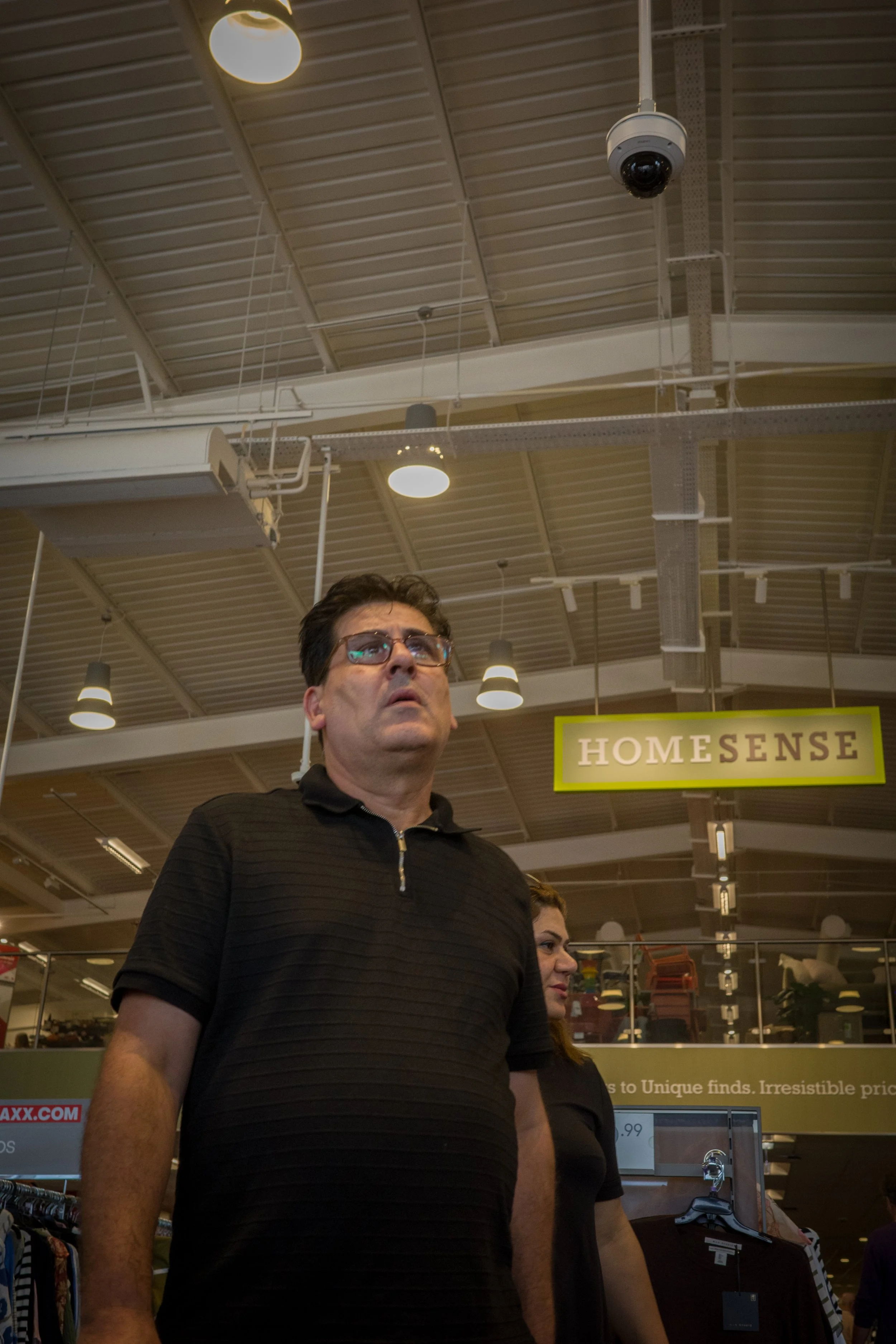 A man and woman shopping inside a store with a sign that reads 'HOMESENSE' hanging from the ceiling.