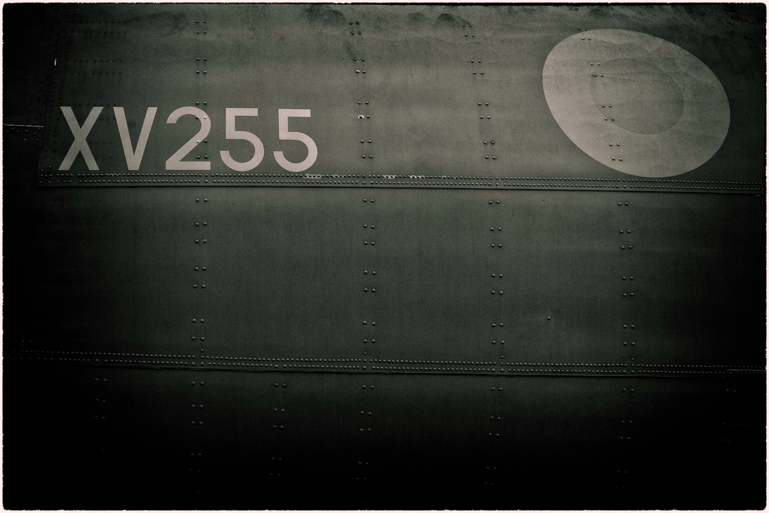 Close-up of a metal surface with rivets, displaying the identification number 'XV255' and a large circular design.