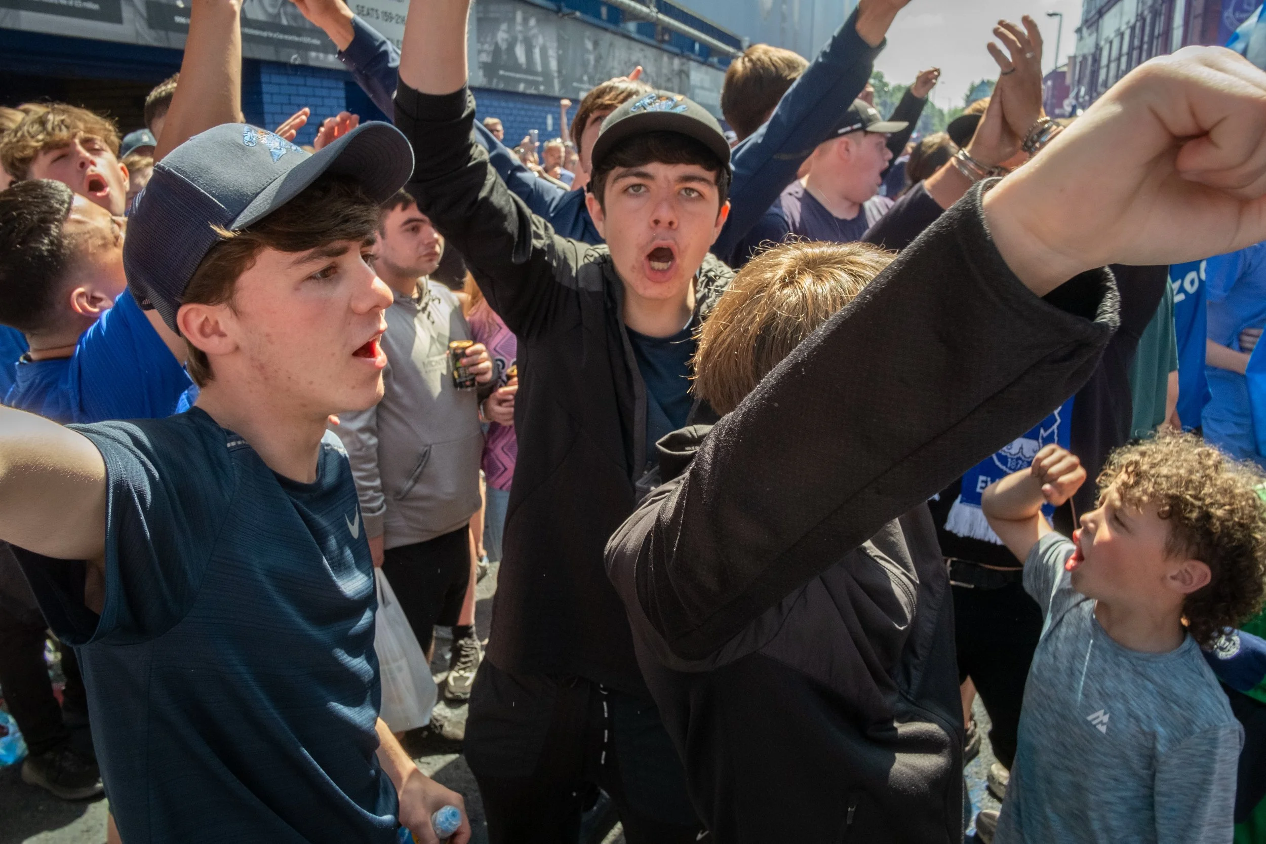 A group of young people, mostly boys, participating in a protest or demonstration outdoors. Some are raising their fists, and expressions show enthusiasm or protest.