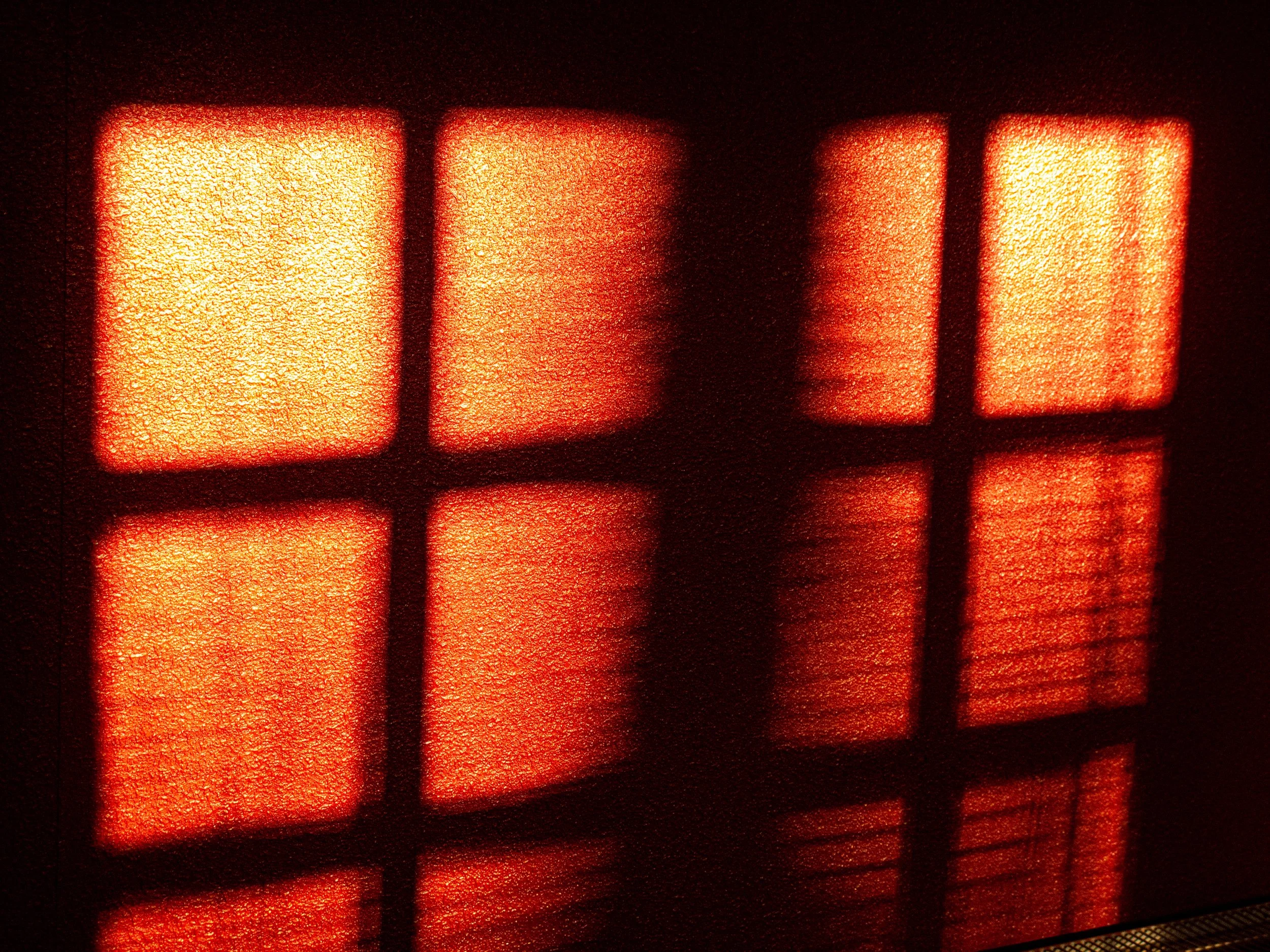 Close-up of illuminated red LCD display with four rectangular segments, each with a bright orange glow and textured surface.