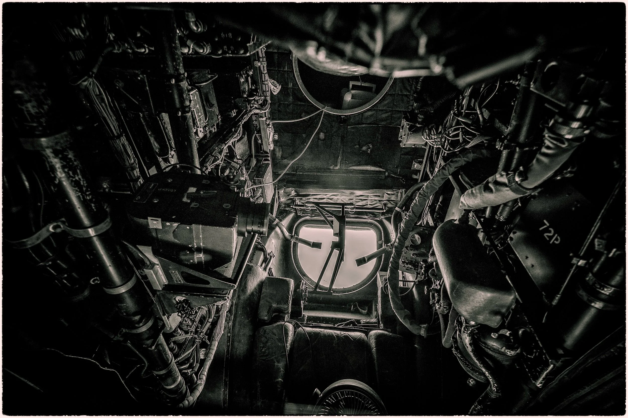 View of the interior of a spacecraft or aircraft with numerous wires, panels, and mechanical components, seen from the back towards the front.