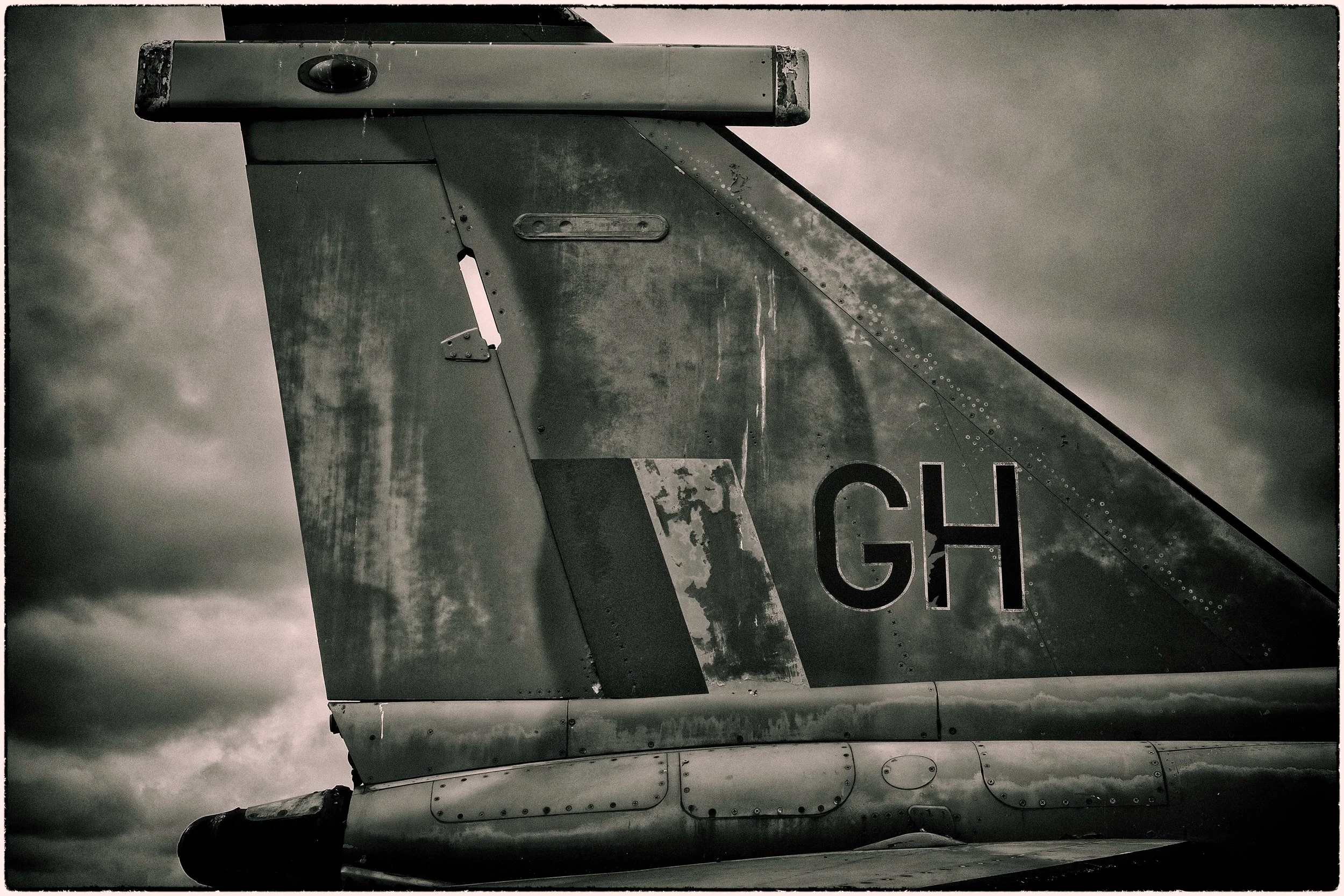 Close-up of the tail section of an aircraft, showing weathered metal surfaces, rivets, and part of the aircraft's identification marking.