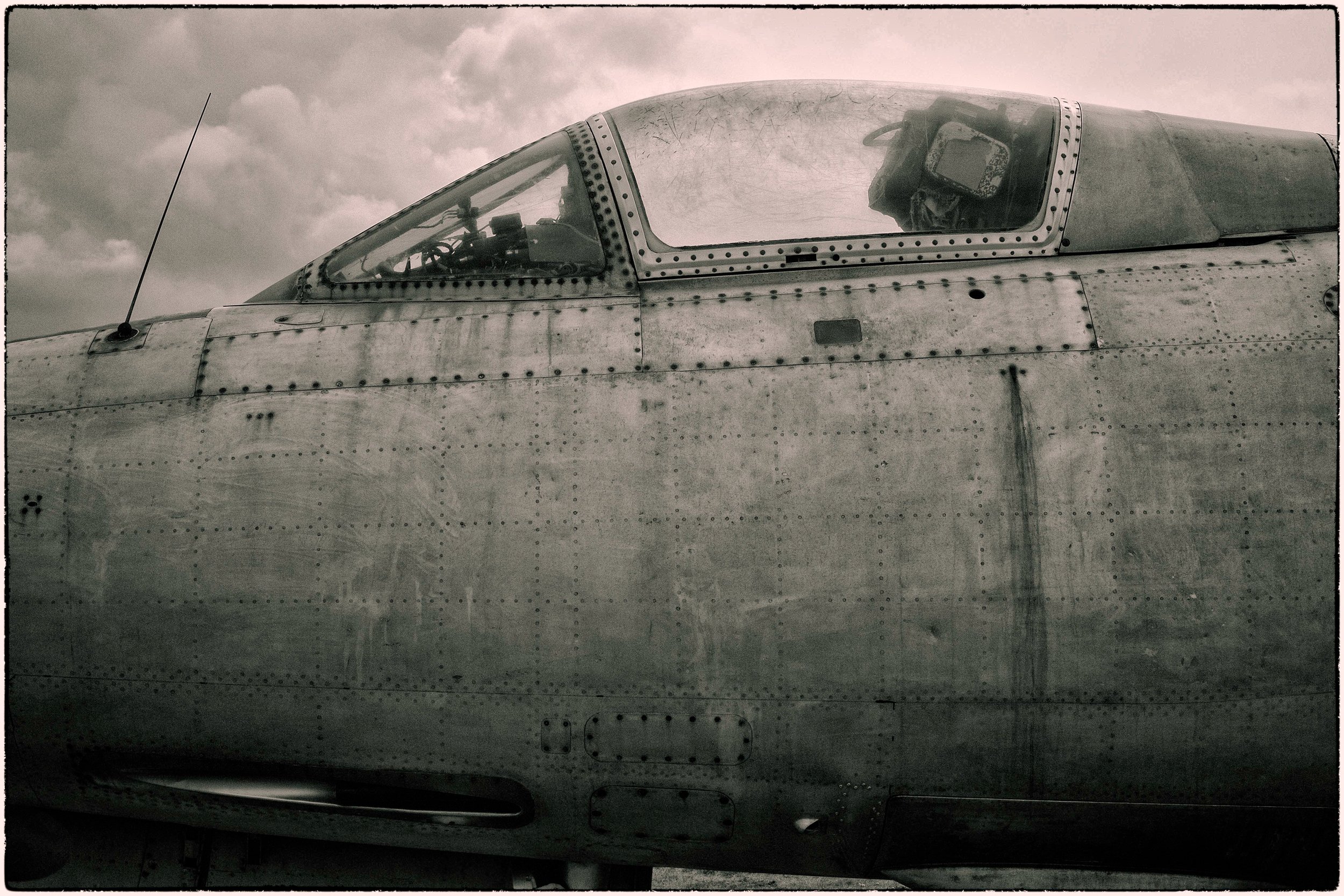 Close-up of the cockpit of a vintage military aircraft with a weathered metal surface and rivets.