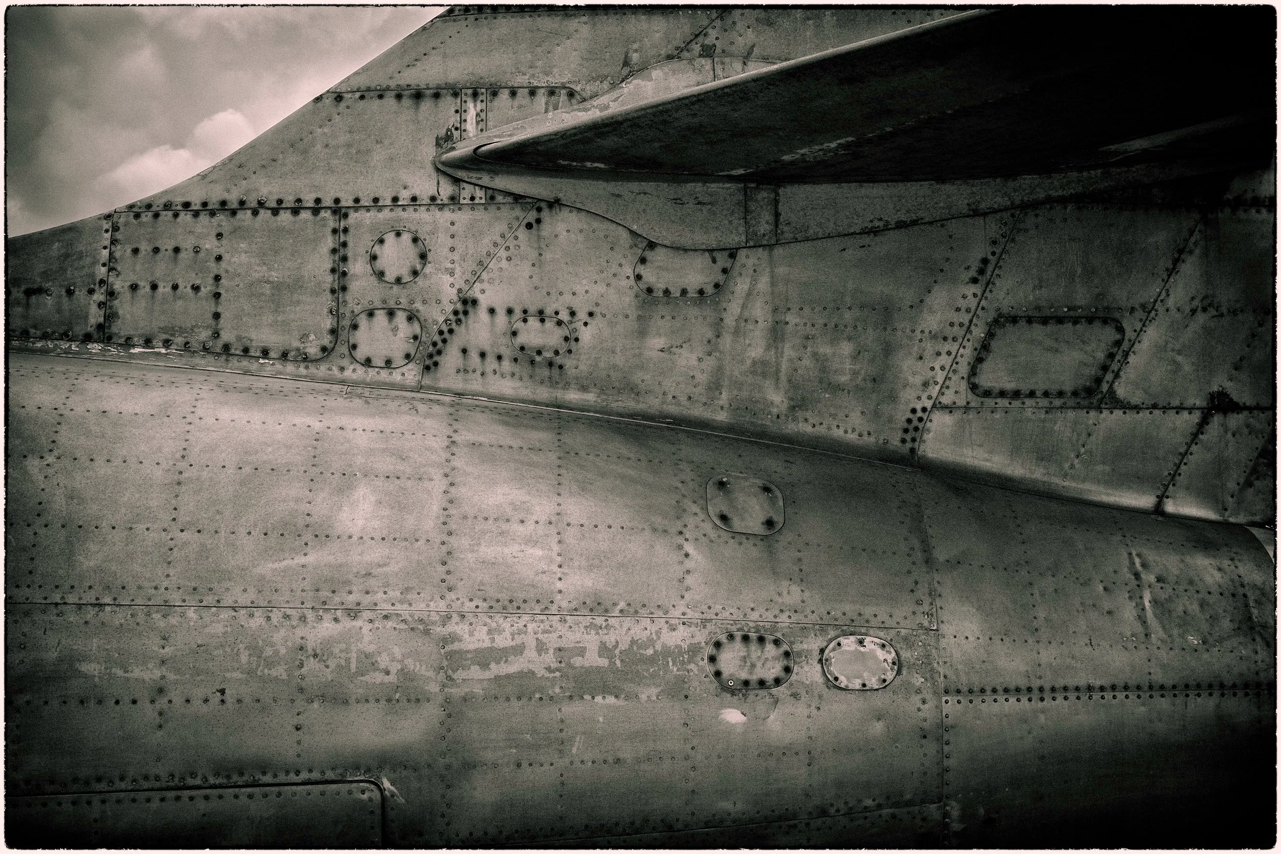 Close-up of the metallic surface of an aircraft wing with visible rivets and panel lines.