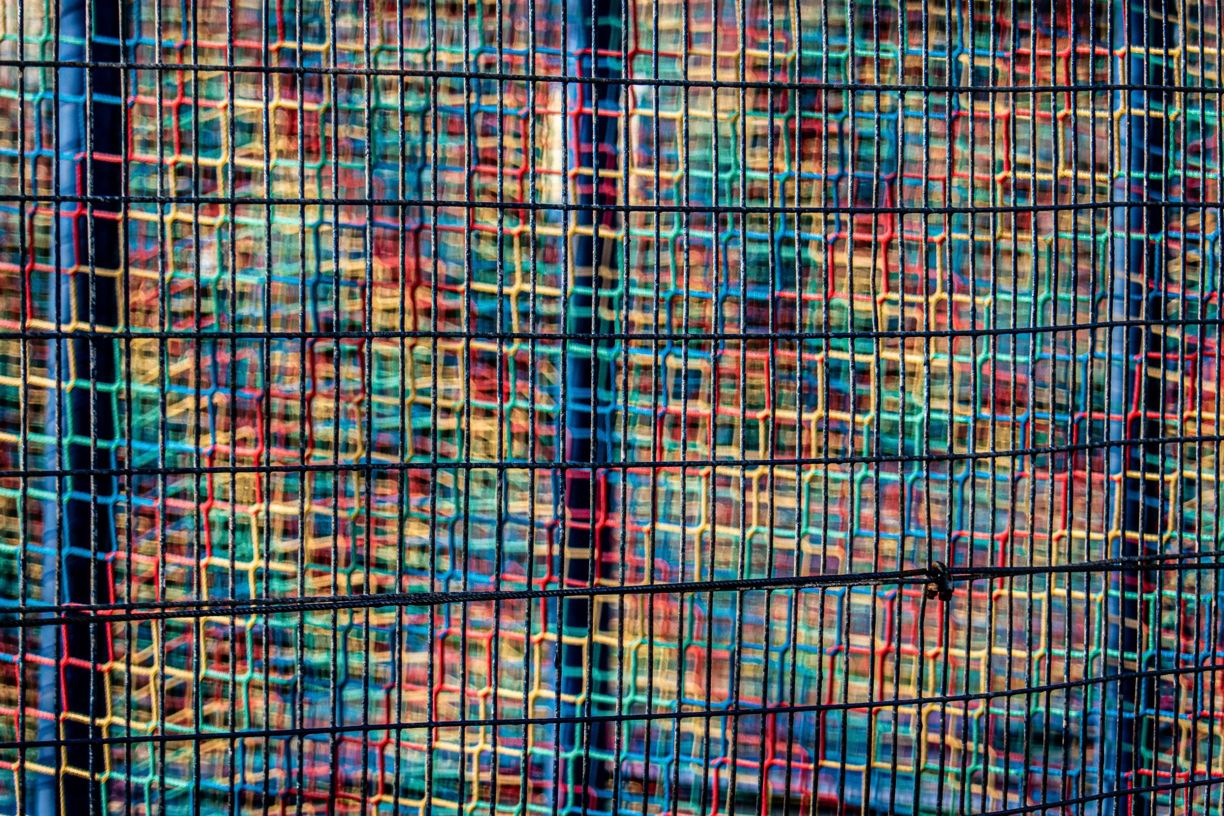 Colorful woven plastic skate park barrier with black metal grid in front