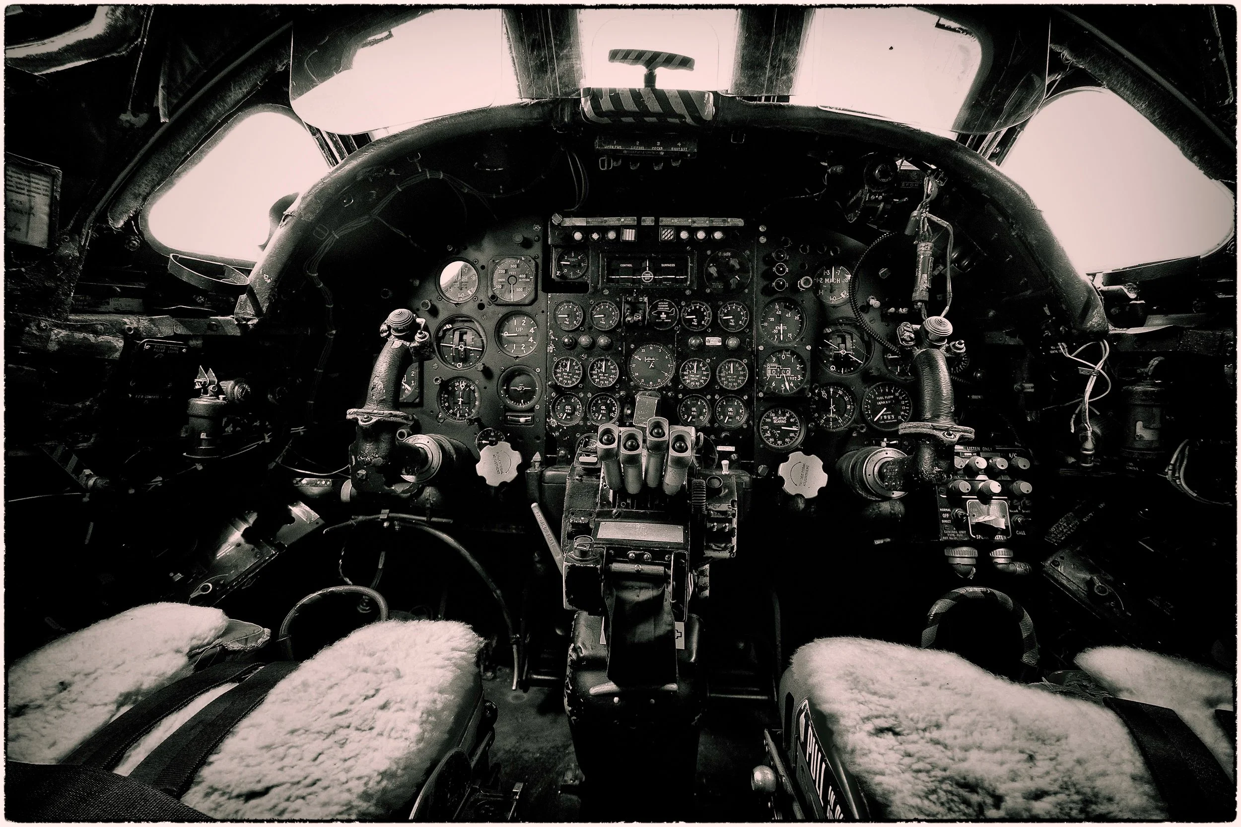 Inside the cockpit of an aircraft showing numerous gauges and controls, with snow visible on the seats.