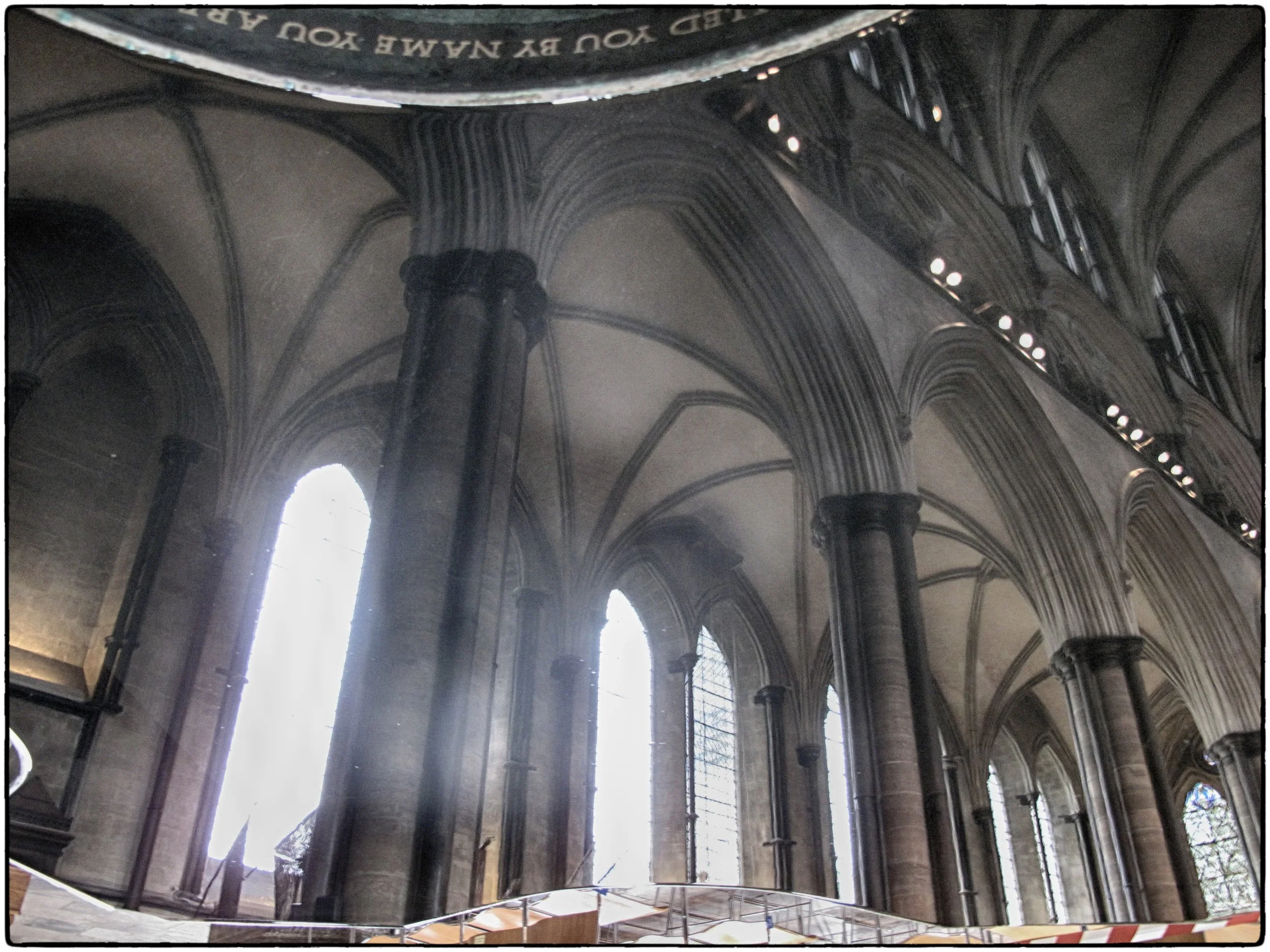 Interior of a gothic cathedral with tall pointed arch windows and columns, sunlight streaming through the windows, and a high vaulted ceiling.