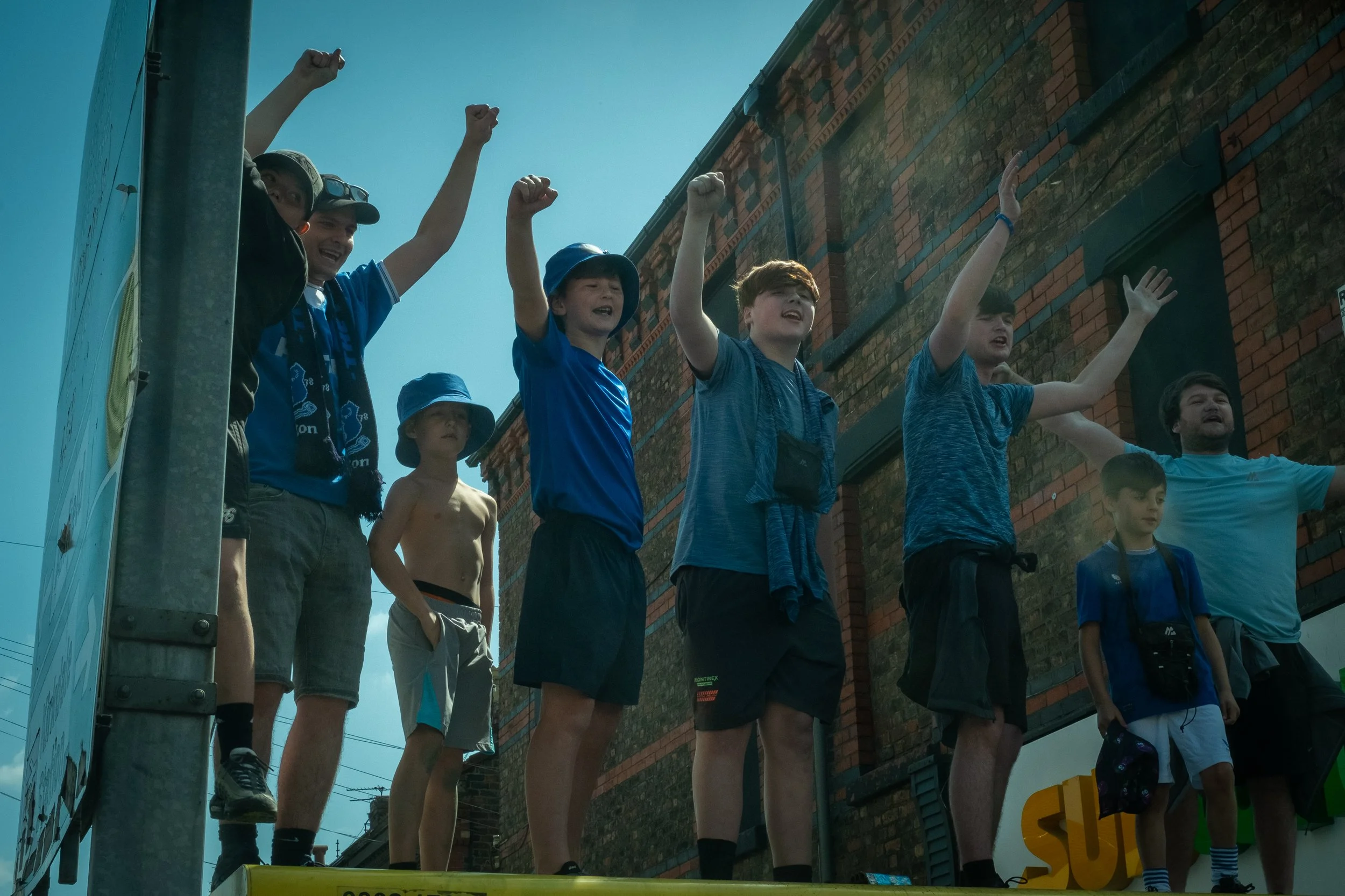 Group of children and adults raising their hands on a parade float.